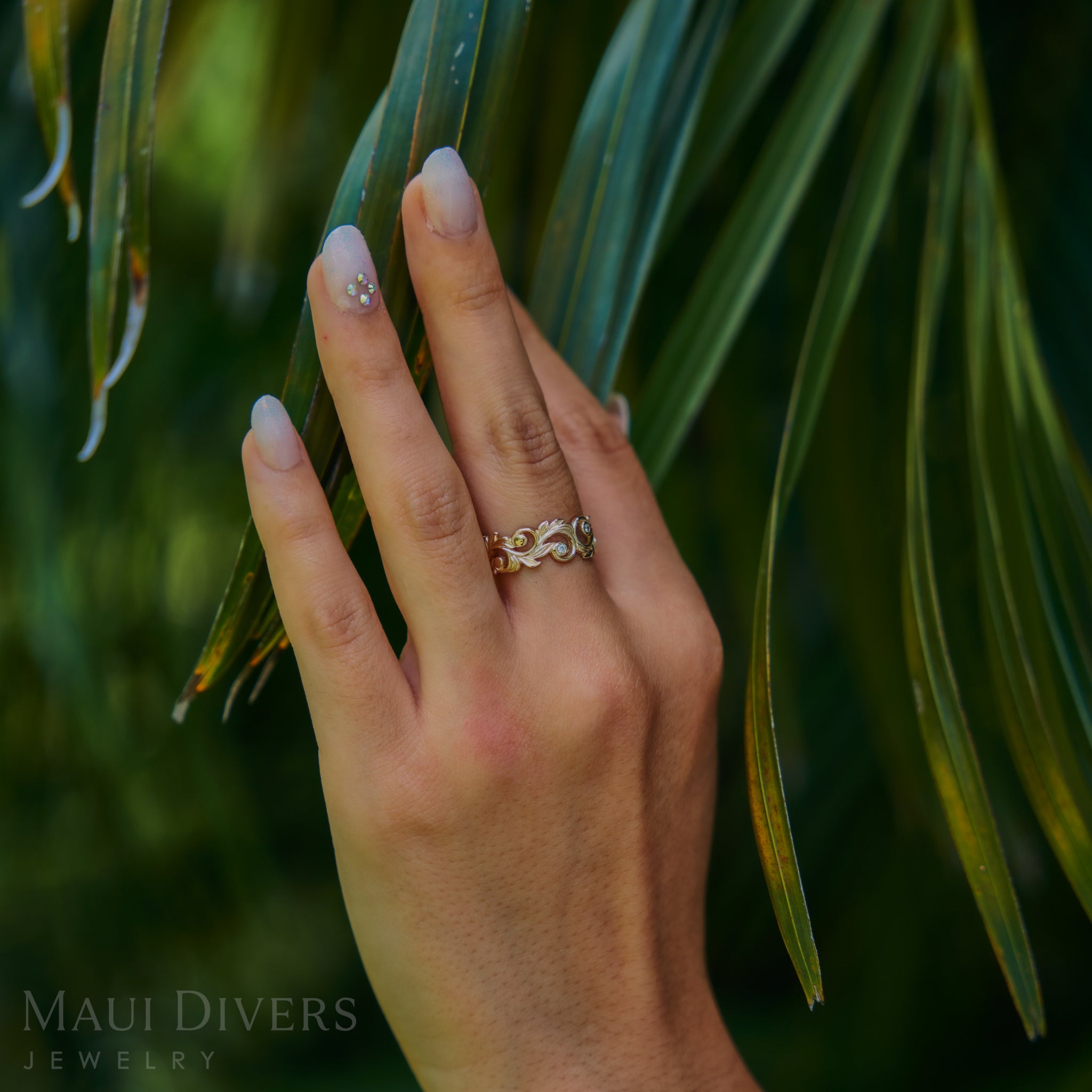 Hand up against a palm leaf wearing Living Heirloom Ring in Gold with Diamonds
