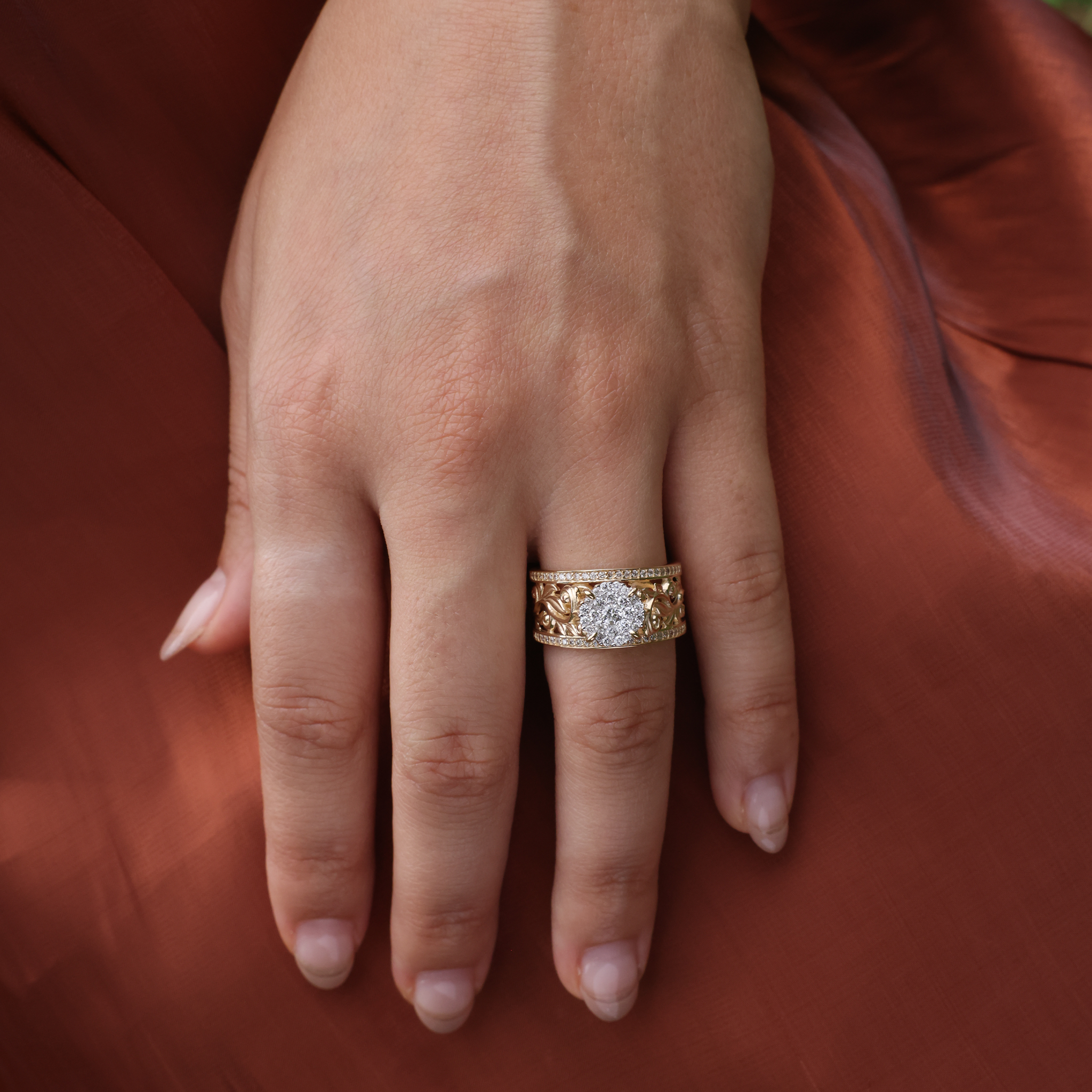 A woman's hand wearing a Living Heirloom Engagement Ring in Gold with Diamonds against a brown dress