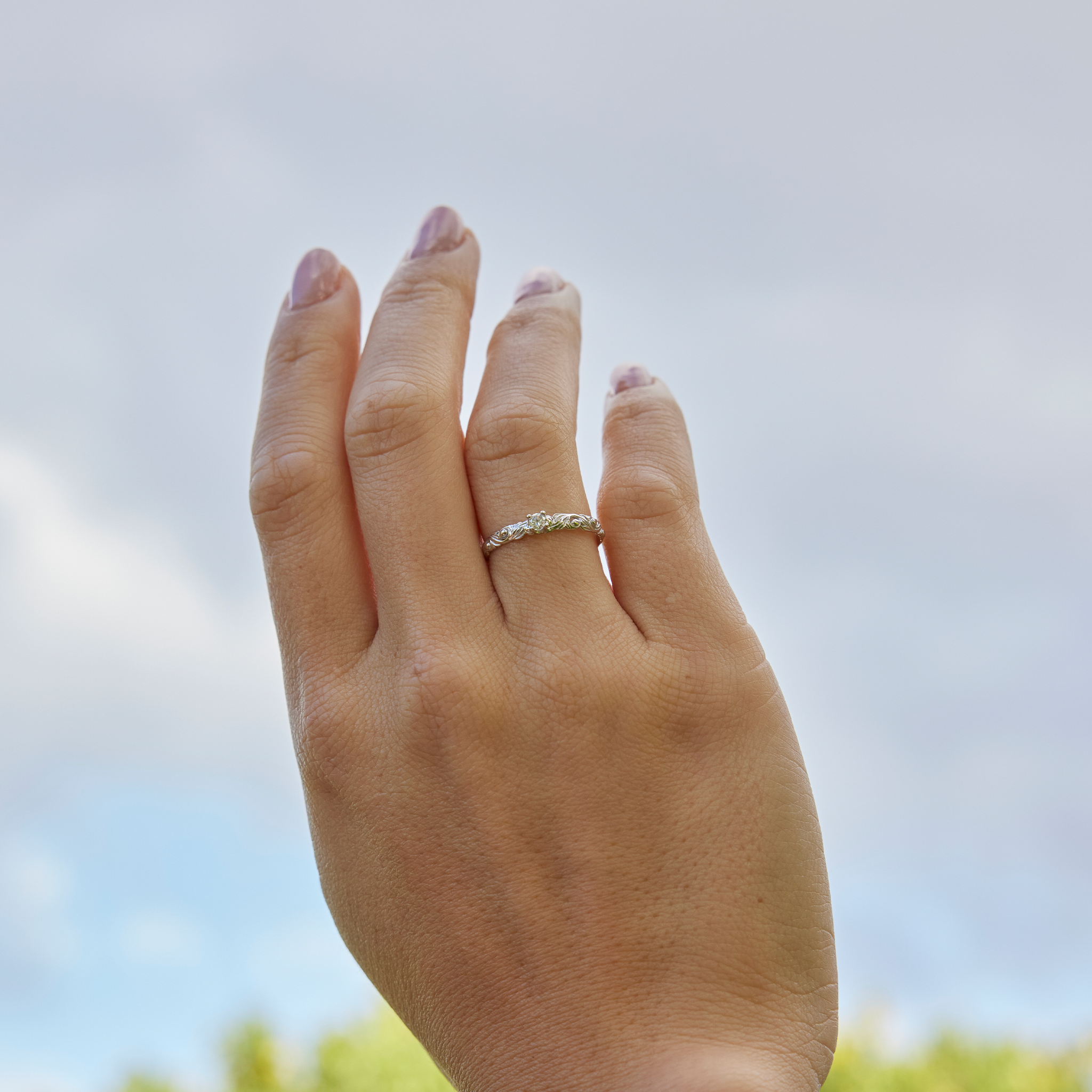 Living Heirloom Ring in White Gold with Diamonds on a woman's hand with blurred sky in the back