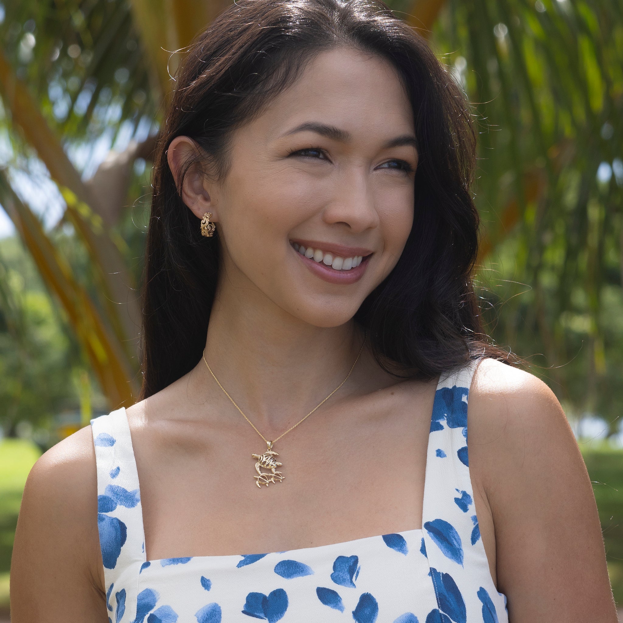 Woman in a park wearing Living Heirloom Hoop Earrings in Gold with Diamonds and honu pendant