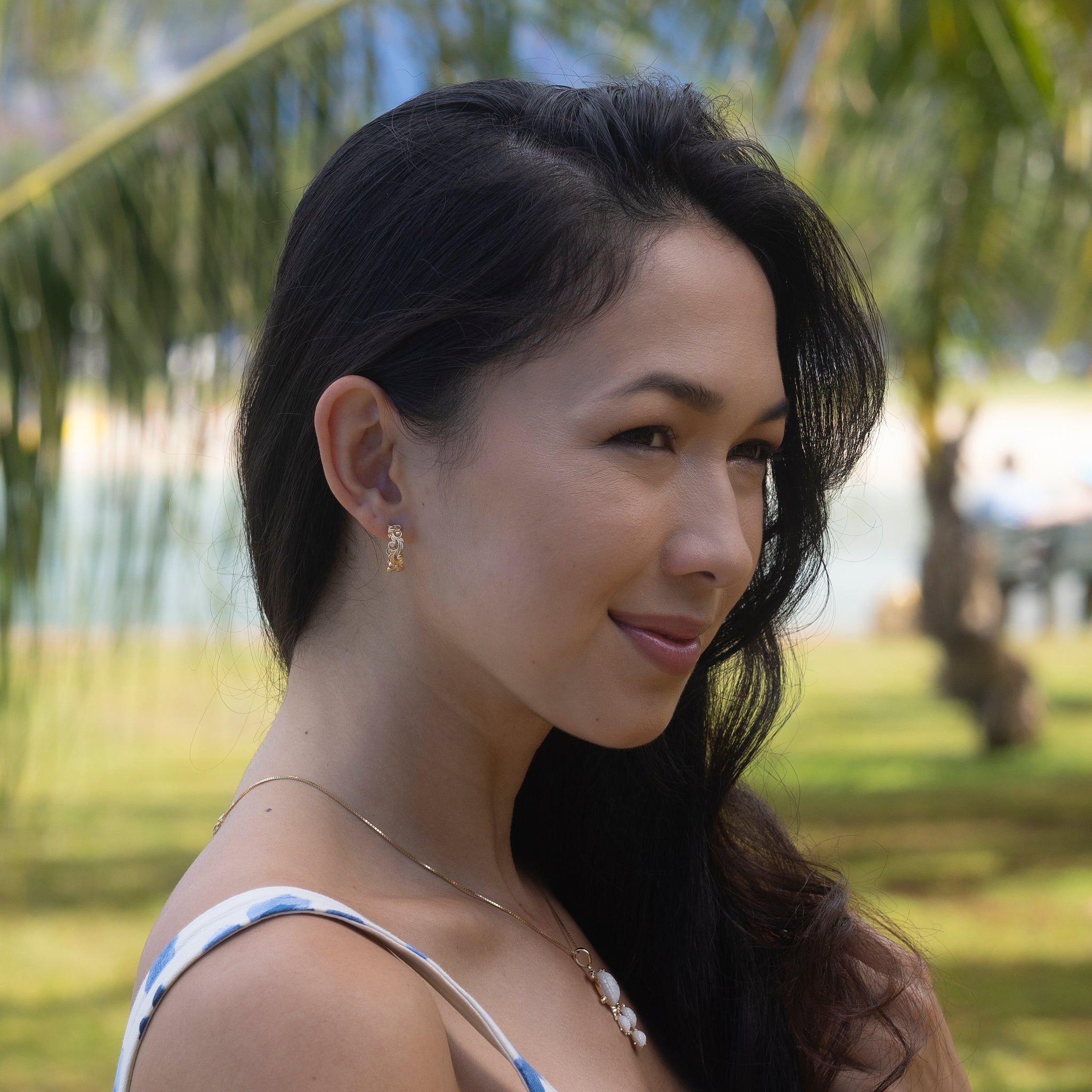 Woman in a beach park wearing Living Heirloom Hoop Earrings in Gold with Diamonds