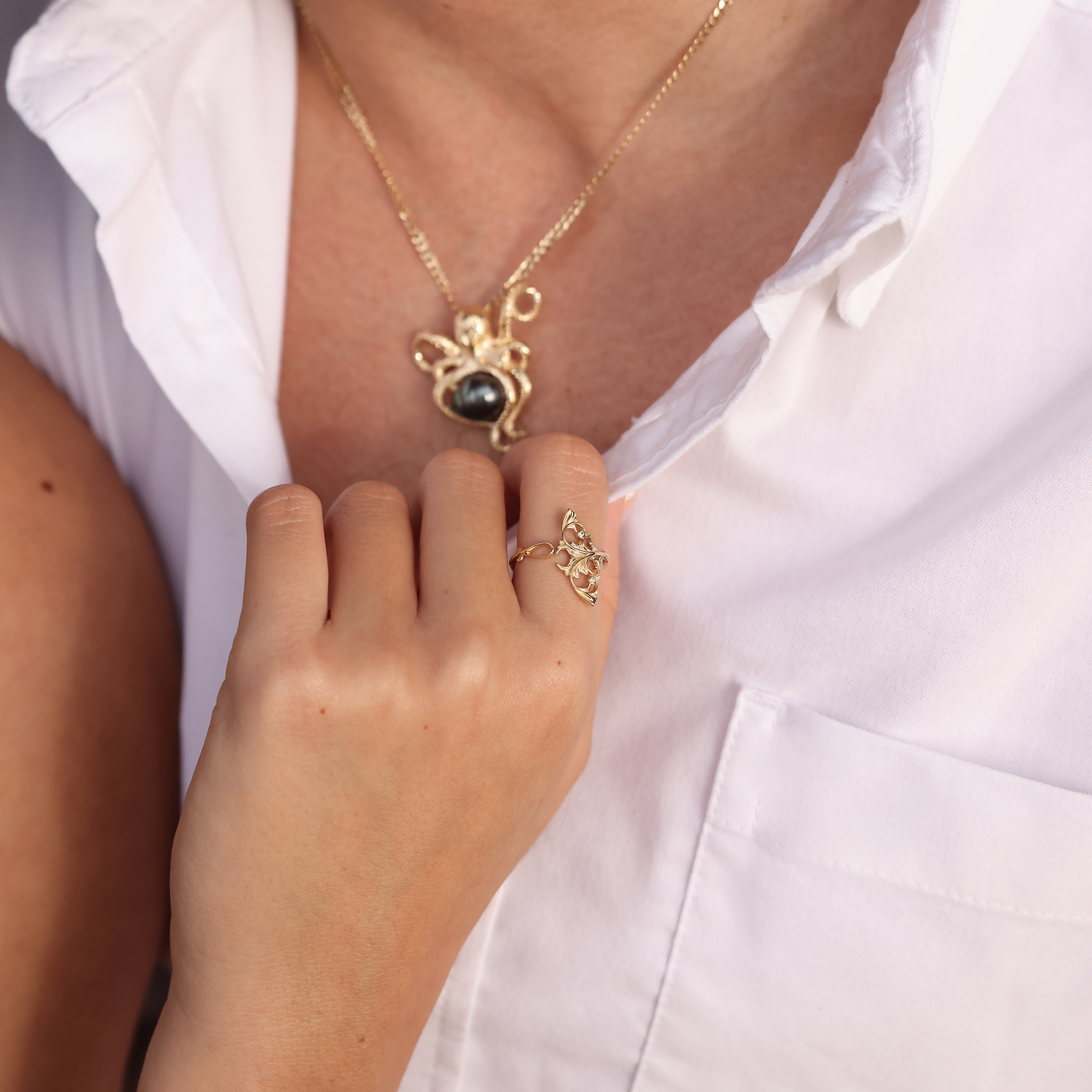 Woman's hand with a Living Heirloom Manta Ray Ring in Gold with Diamonds holding a person's shirt collar