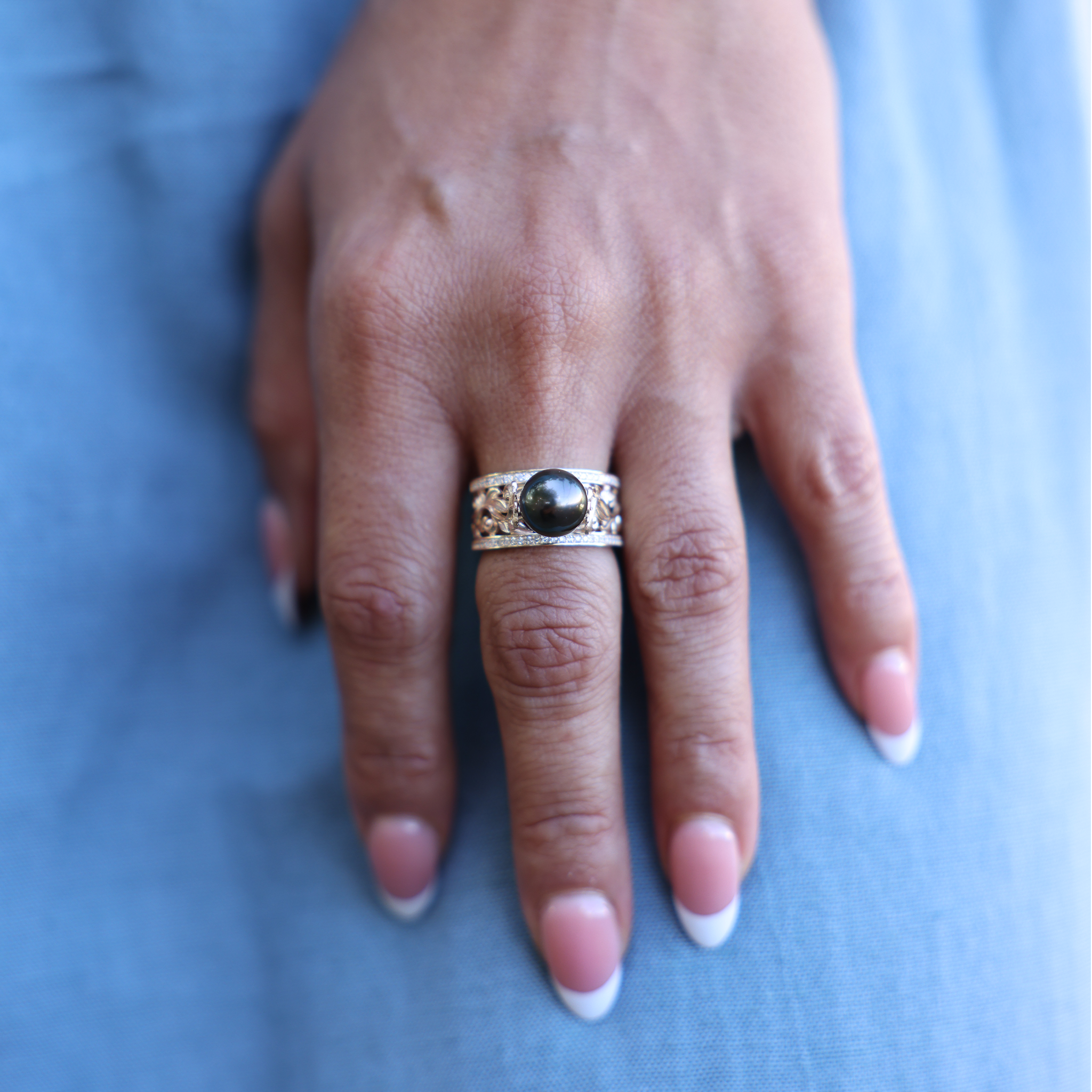 Hawaiian Heirloom Tahitian Black Pearl Ring in Gold with Diamonds on Hand over blue dress