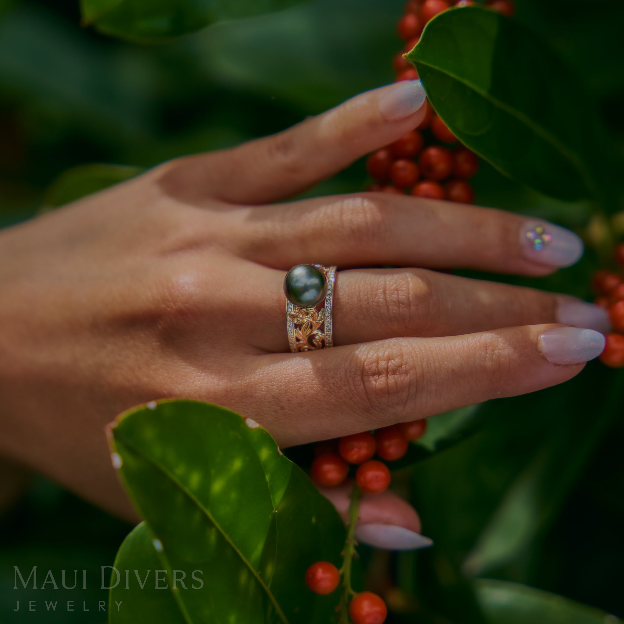 Hand wearing a Living Heirloom Tahitian Black Pearl Ring in Gold with Diamonds with berries and leaves in the background