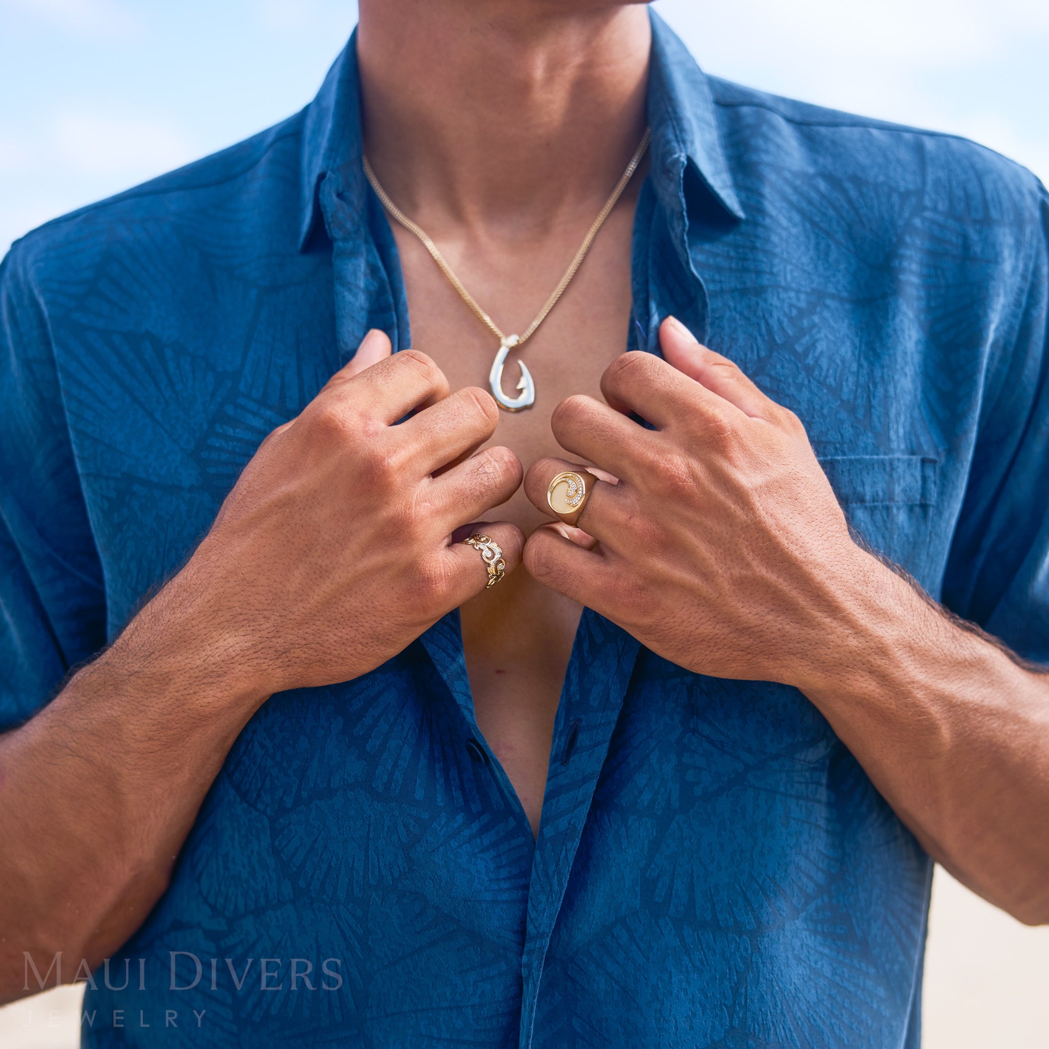 Person wearing a blue shirt with a Nalu and Living Heirloom Ring in Gold with Diamonds against a blue sky