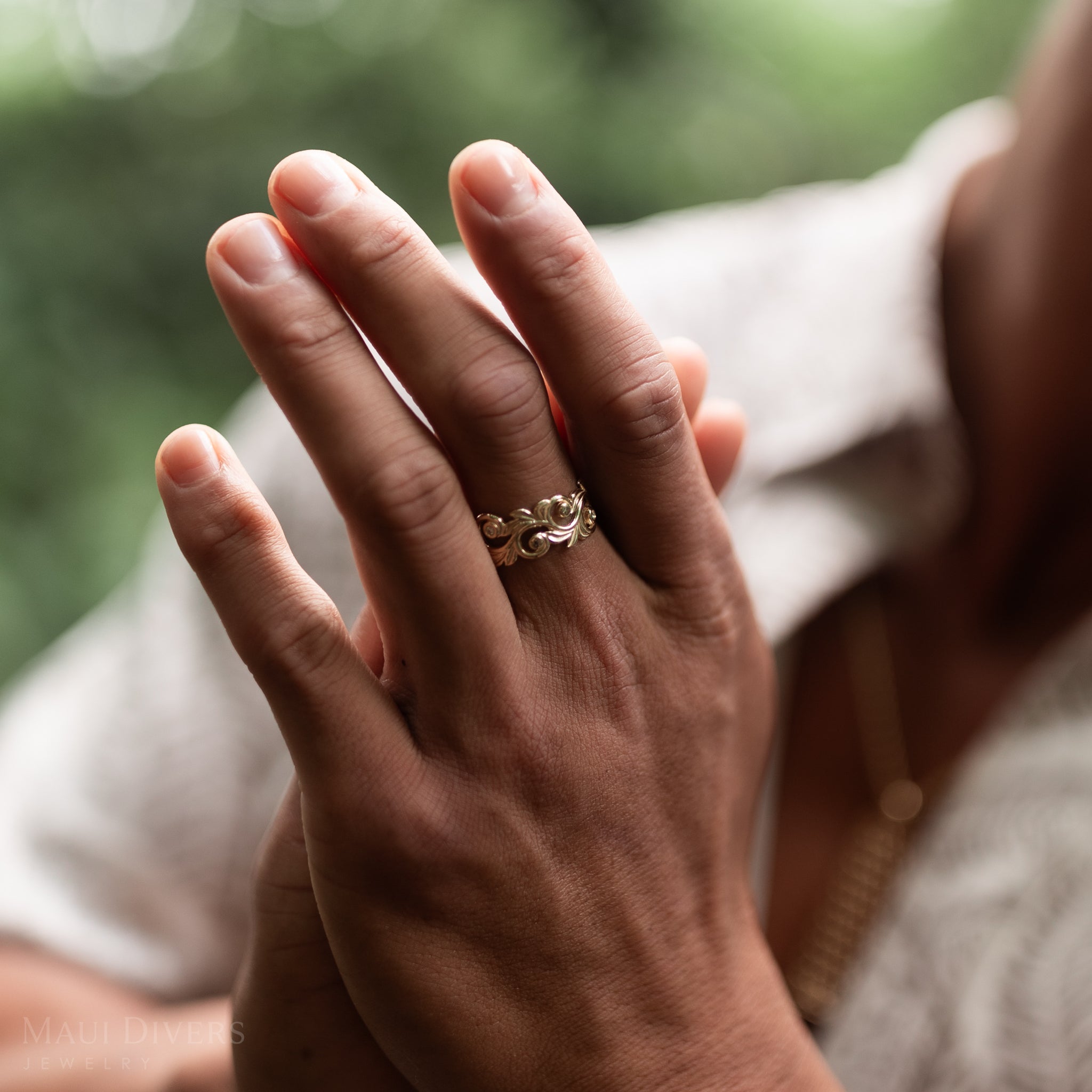 Close up of Living Heirloom Ring in Gold with Diamonds on a man's hands with blurred green background
