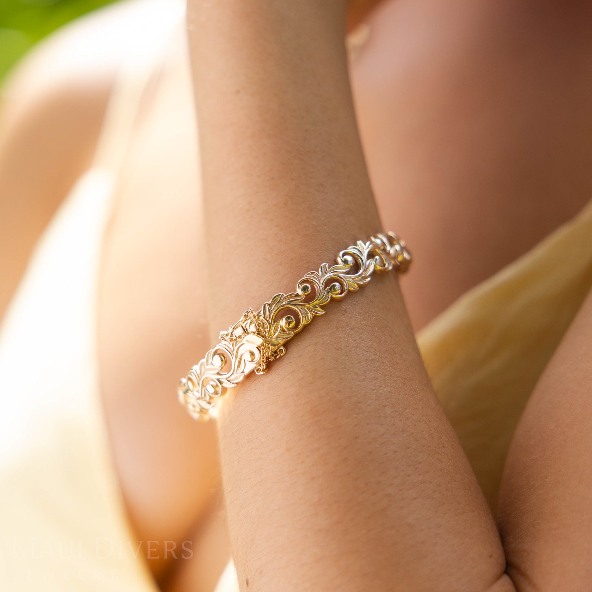 Close-up of a Living Heirloom Hinge Bracelet in 14k Yellow Gold on a person's wrist with a blurred background