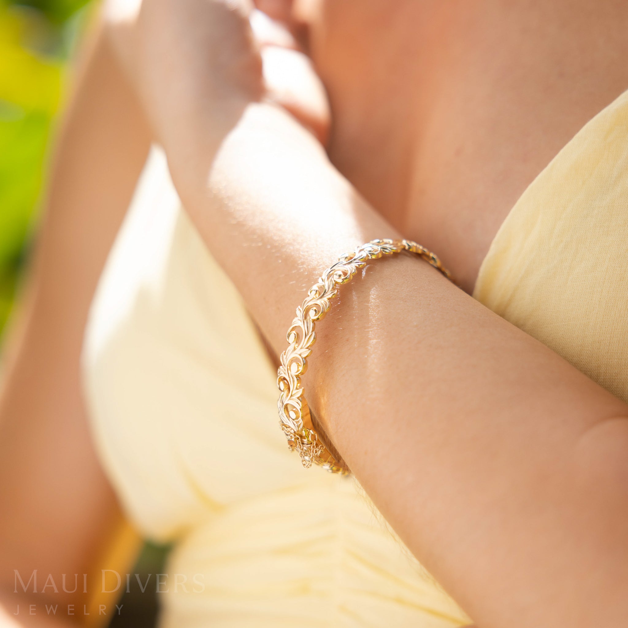 Close-up of a Living Heirloom Hinge Bracelet in 14k Yellow Gold on a wrist with a blurred background