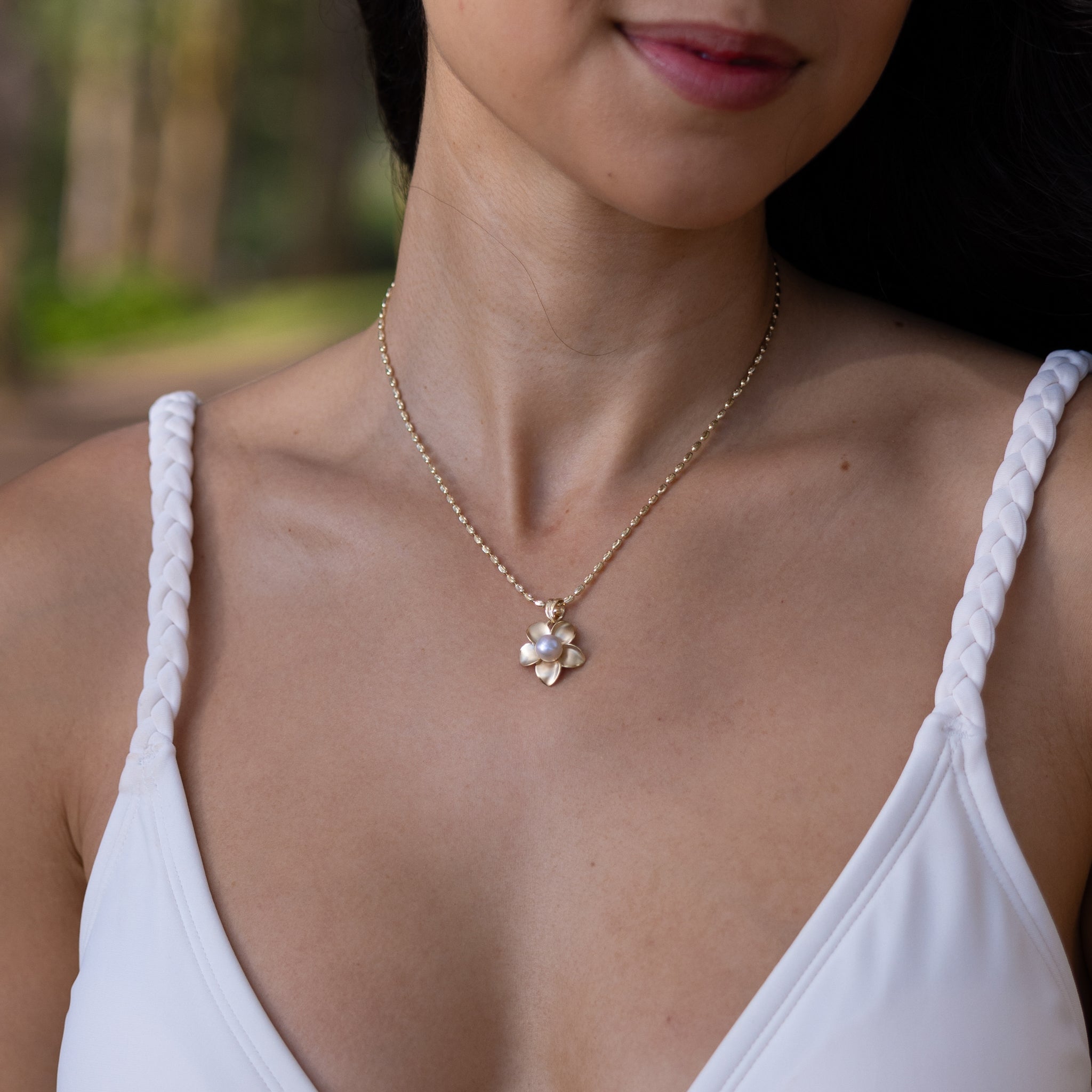 18mm Pick A Pearl Plumeria Pendant in Gold with a Lavender Pearl on a woman's chest outdoors