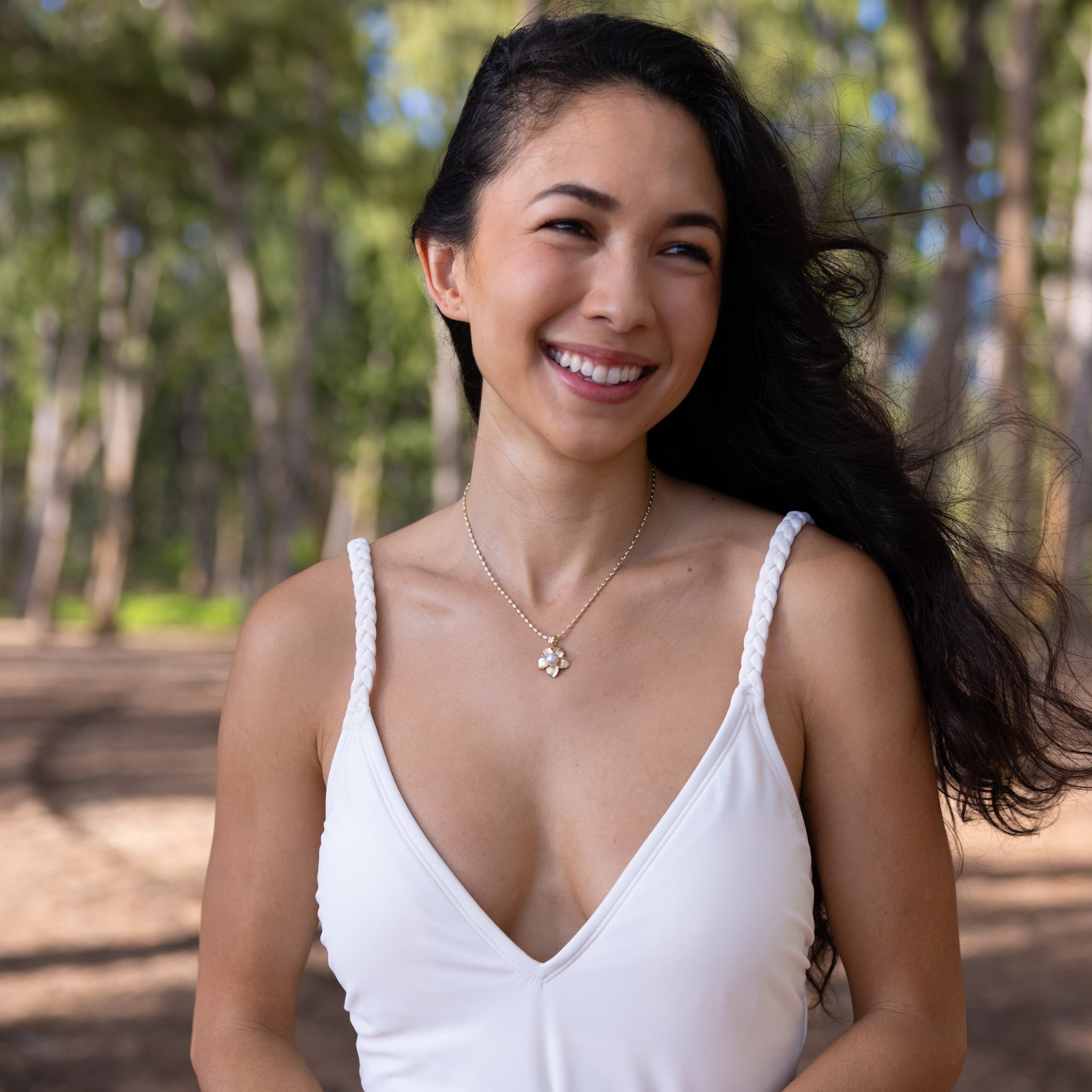 18mm Pick A Pearl Plumeria Pendant in Gold with a Lavender Pearl on a woman at a beach park