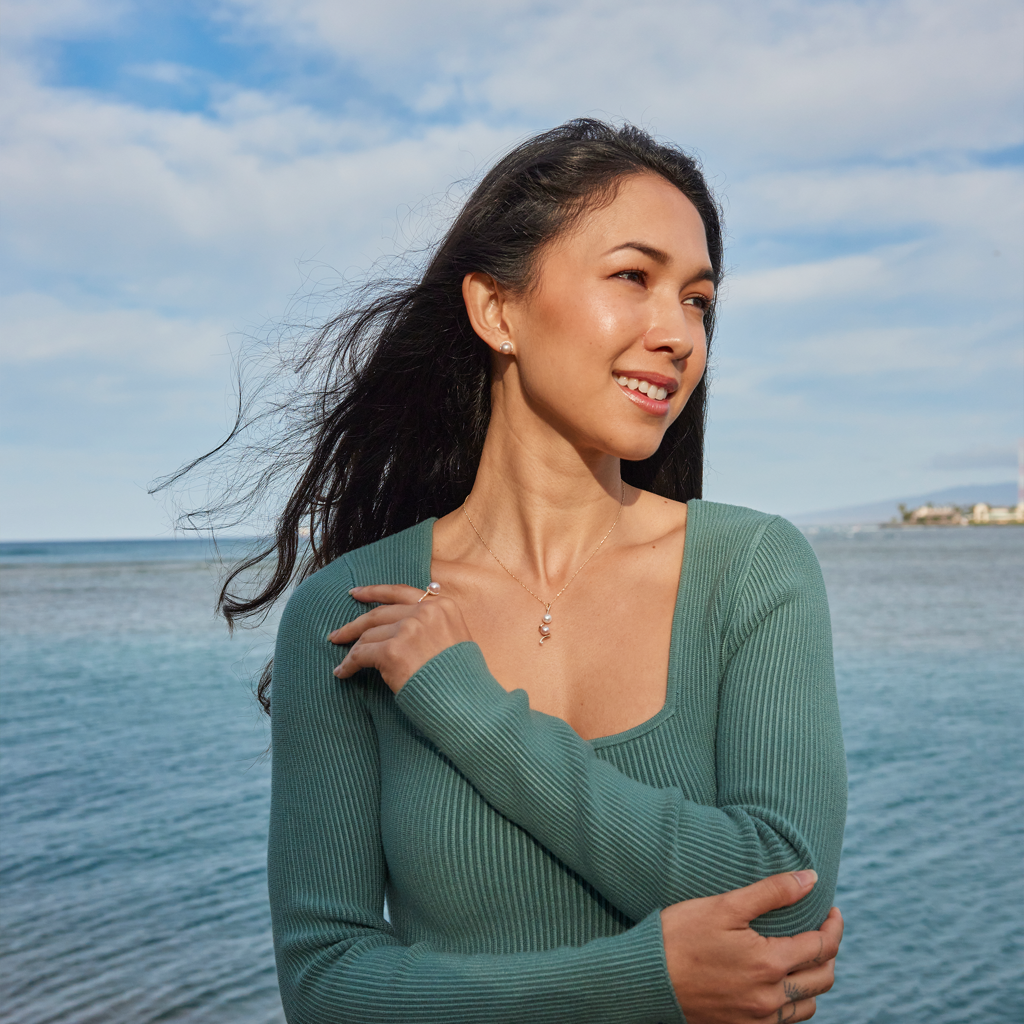 Woman by the ocean wearing a Pick A Pearl Halo Ring in Gold with Diamonds and White Pearl