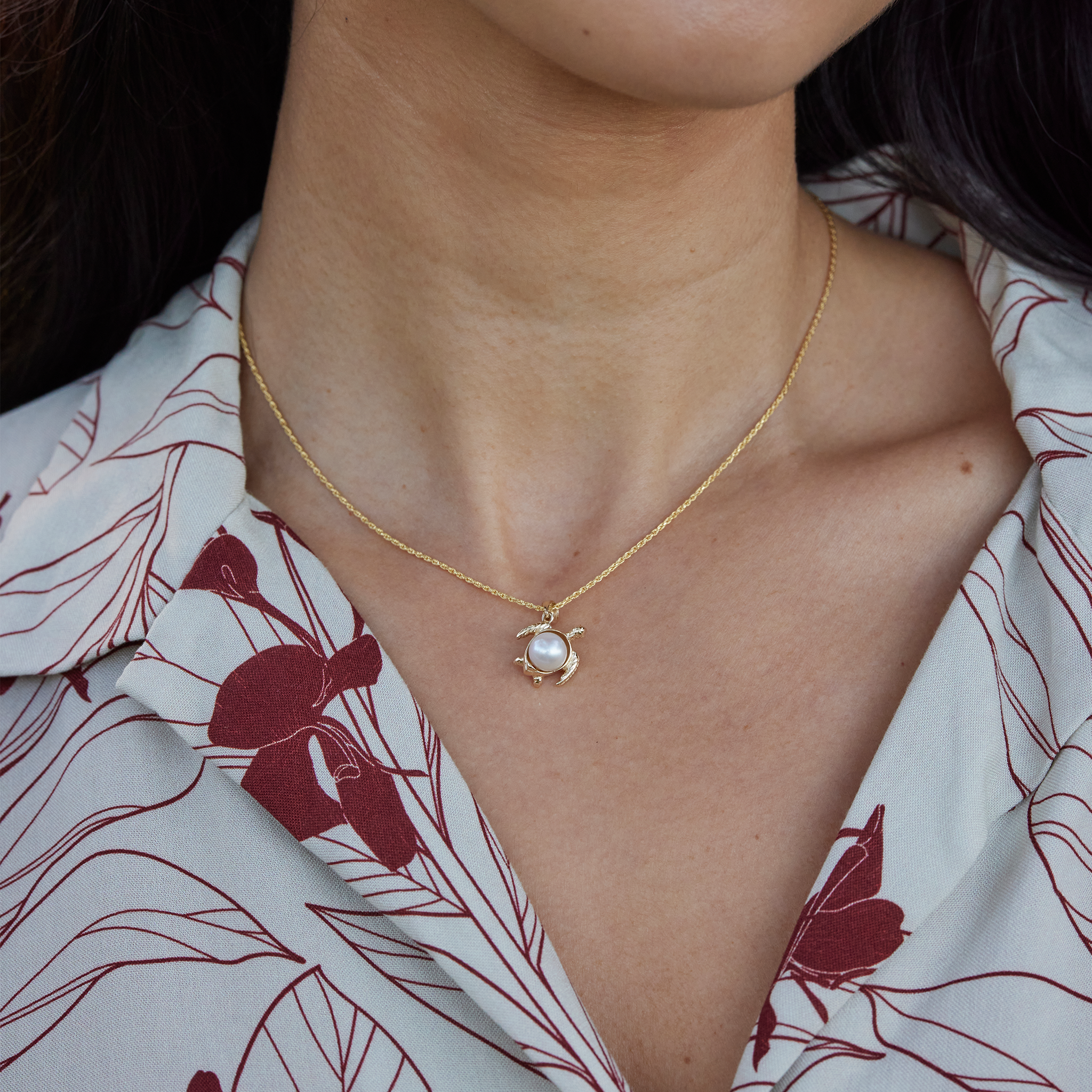 Close up of a 12mm Pick A Pearl Honu Pendant in Gold with a White Pearl on a person's neckline