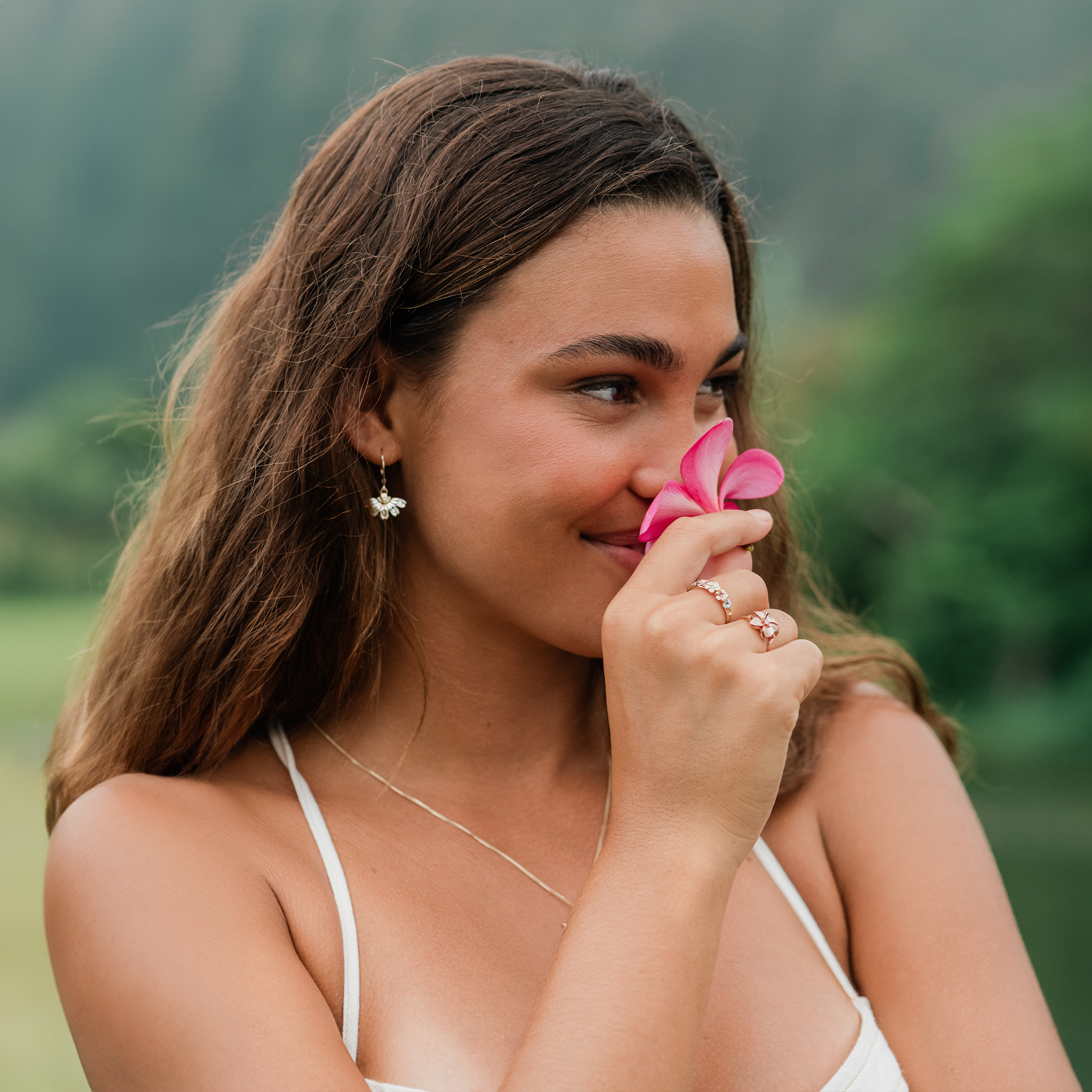Woman smelling a plumeria wearing Plumeria Rings in Tri Color Gold with Diamonds