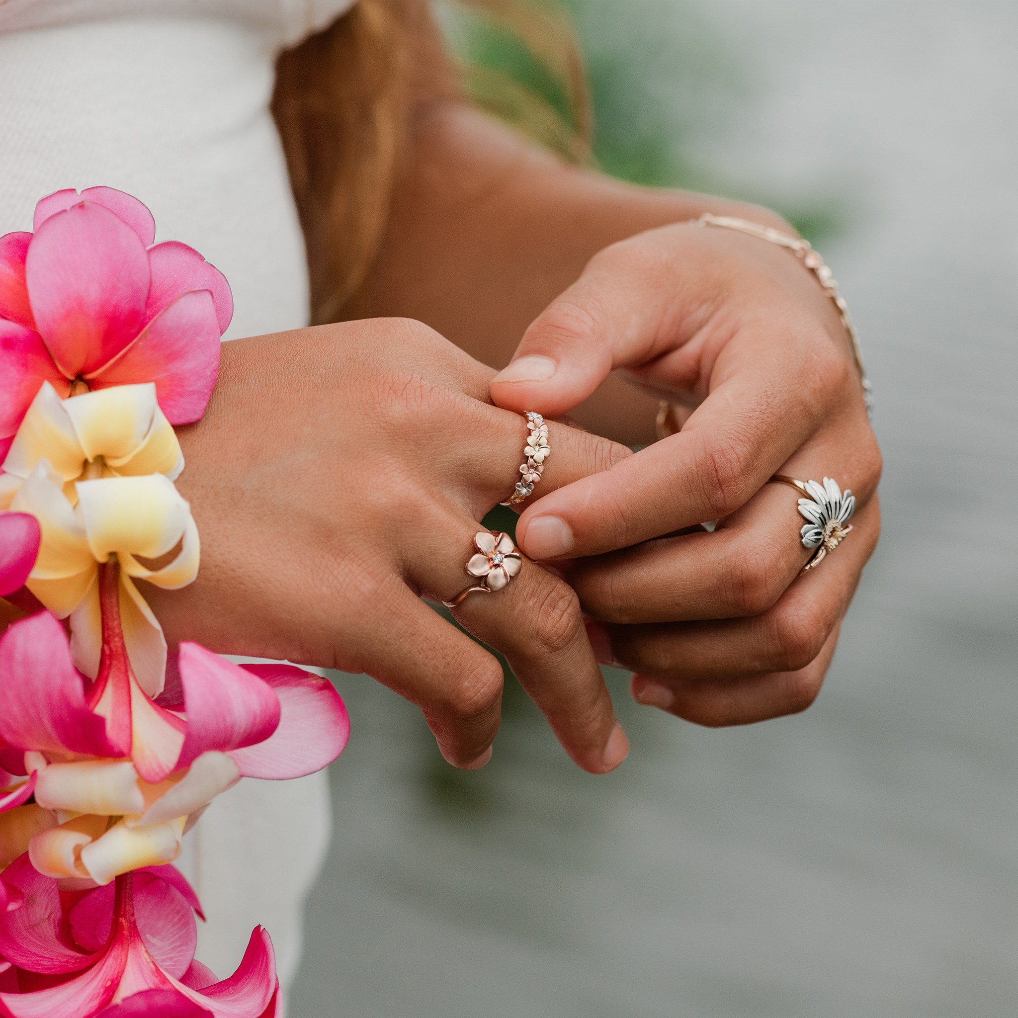 Hands wearing Plumeria and Naupaka Rings in Tri Color Gold with Diamonds