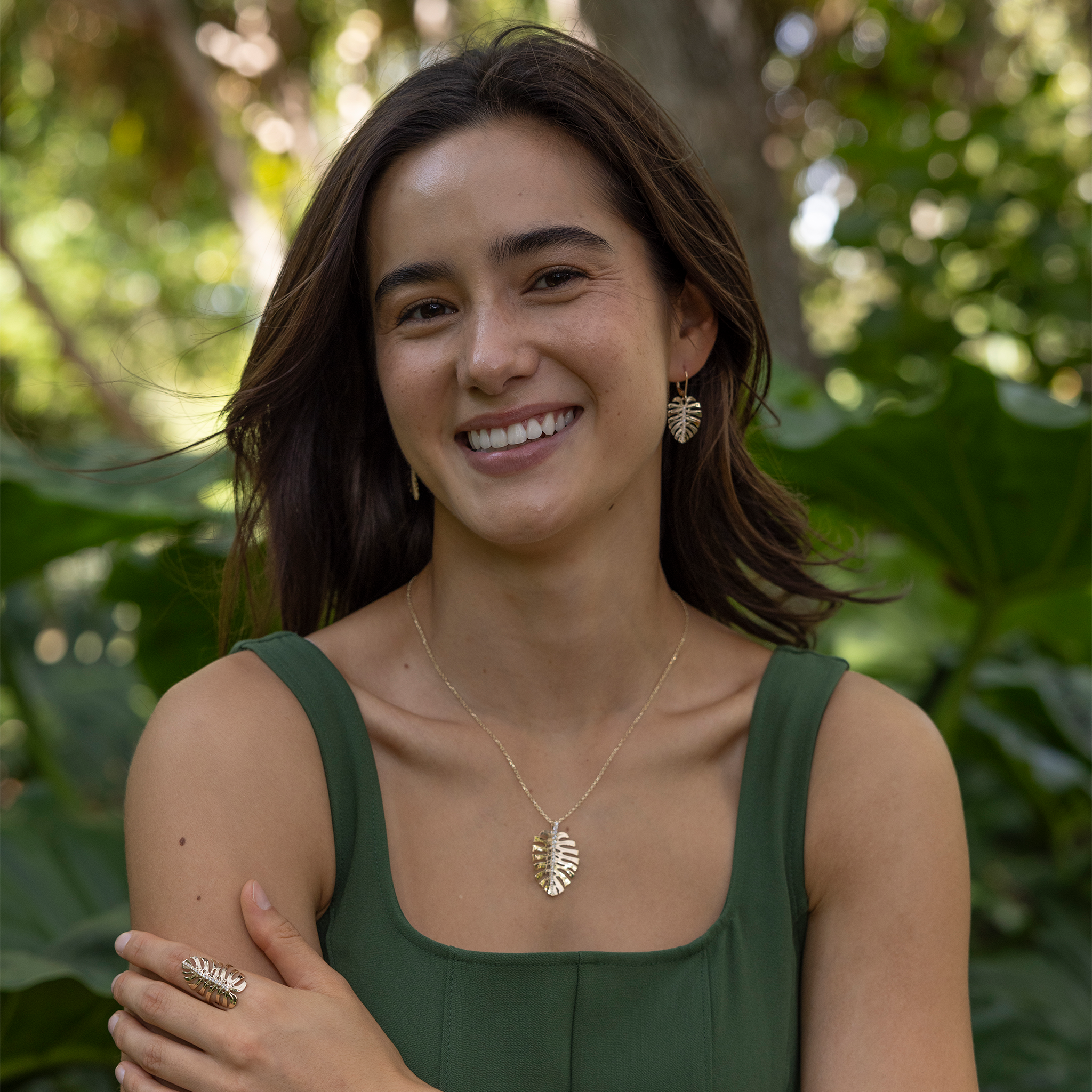 Woman in a garden wearing Monstera Earrings, Pendant and Ring in Gold with Diamonds