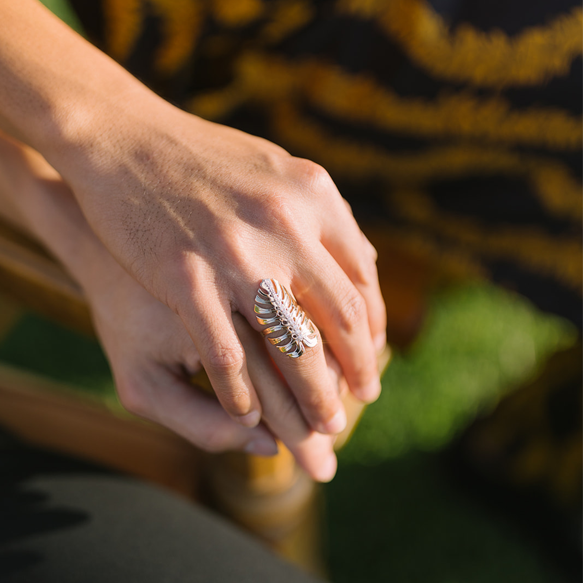 32mm Monstera Ring in Gold with Diamonds on caressing hands in the sunlight