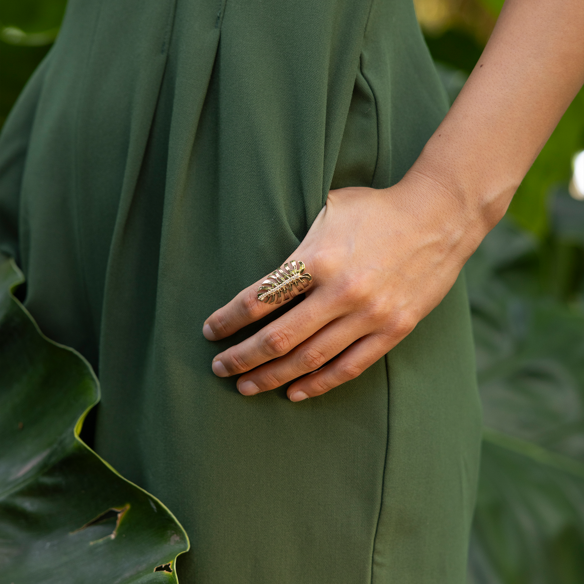 32mm Monstera Ring in Gold with Diamonds on hand hooked in pocket of green jumpsuit outdoors