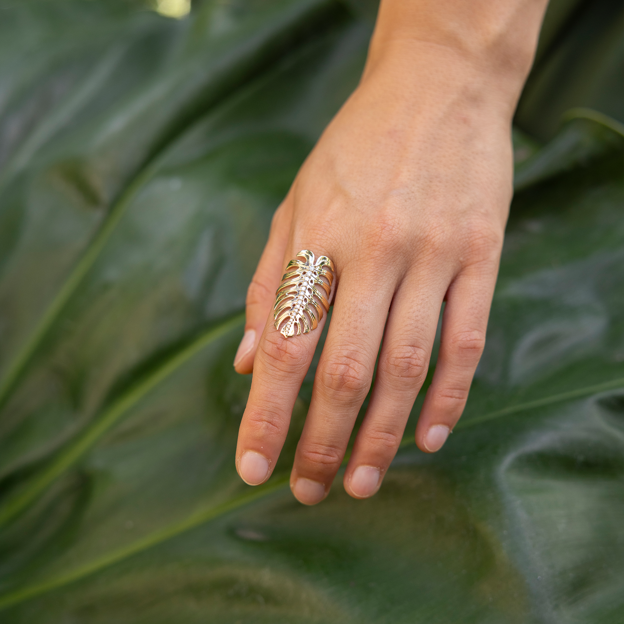 32mm Monstera Ring in Gold with Diamonds on hand over a large green leaf