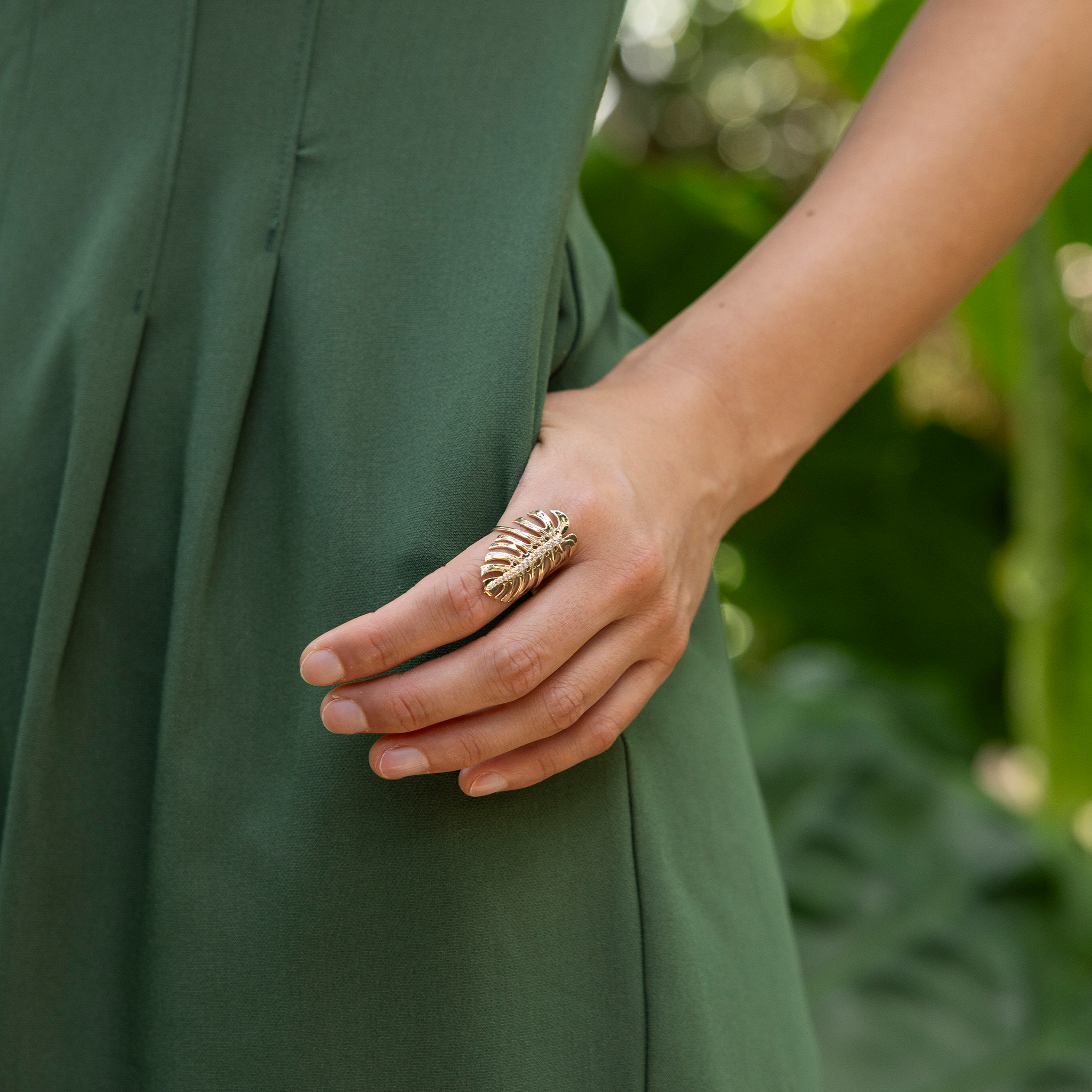 32mm Monstera Ring in Gold with Diamonds on a hand hooked in the pocket of a green jumpsuit outdoors