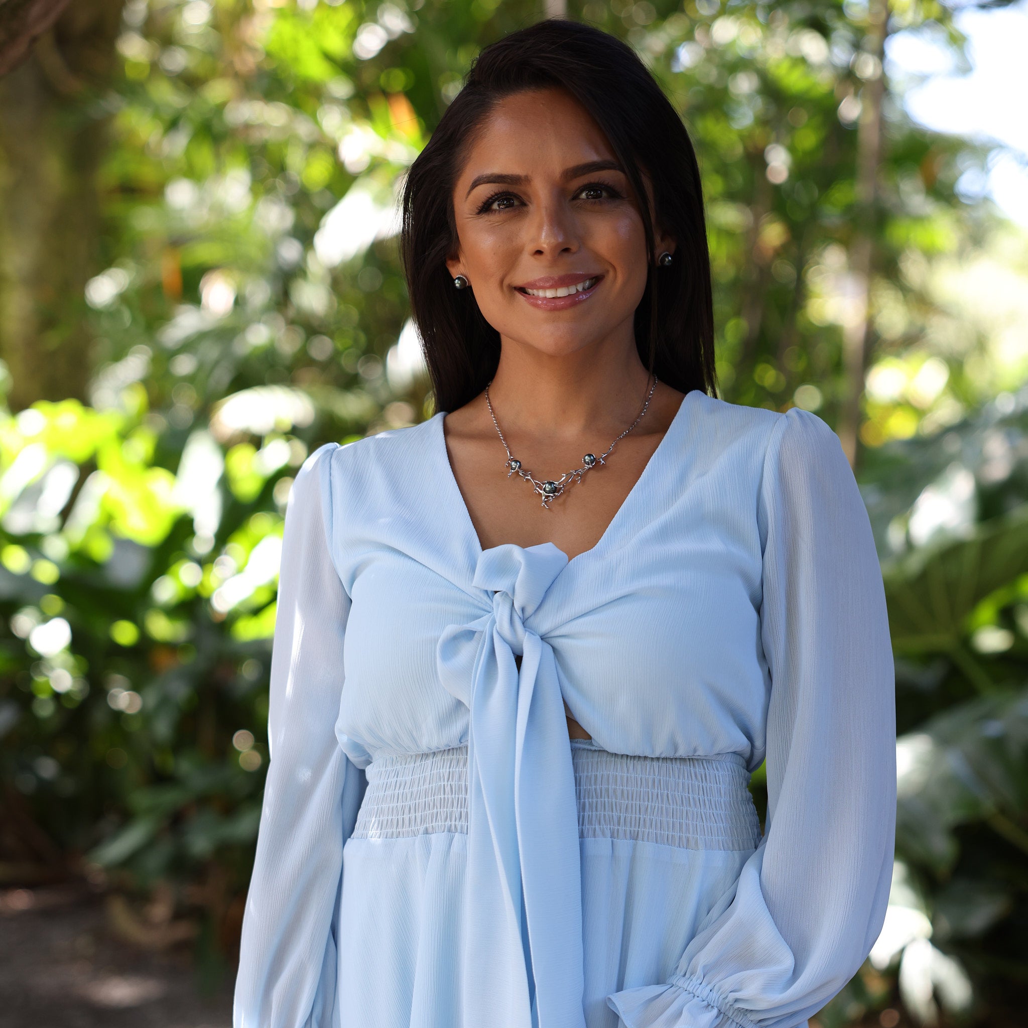 Woman in blue dress wearing Tahitian Black Pearl Earrings in White Gold with Diamonds in Hawaii