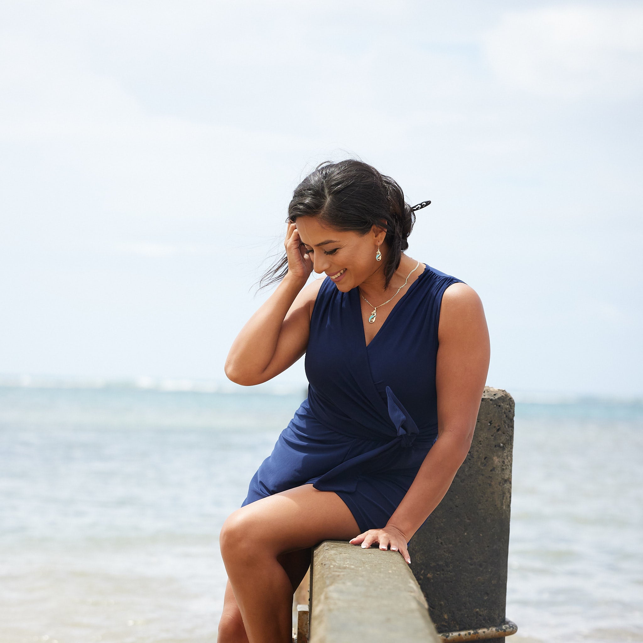 A woman seating on a wall wearing a Sealife Mermaid Turquoise Pendant in Gold with Diamonds - 30mm - Maui Divers Jewelry