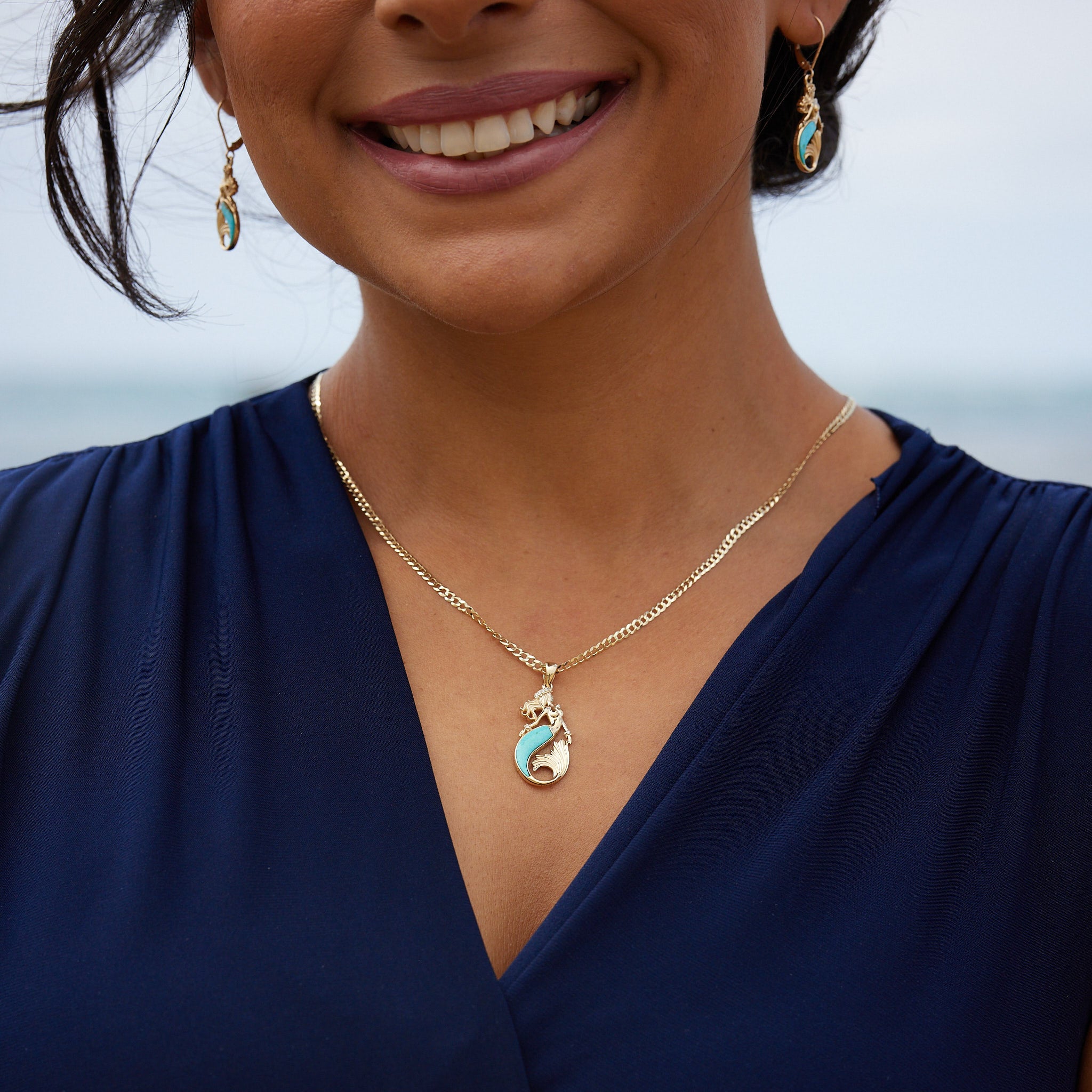 A woman's chest with A Sealife Mermaid Turquoise Pendant in gold with Diamonds - 30mm - and earrings - Maui Divers Jewelry
