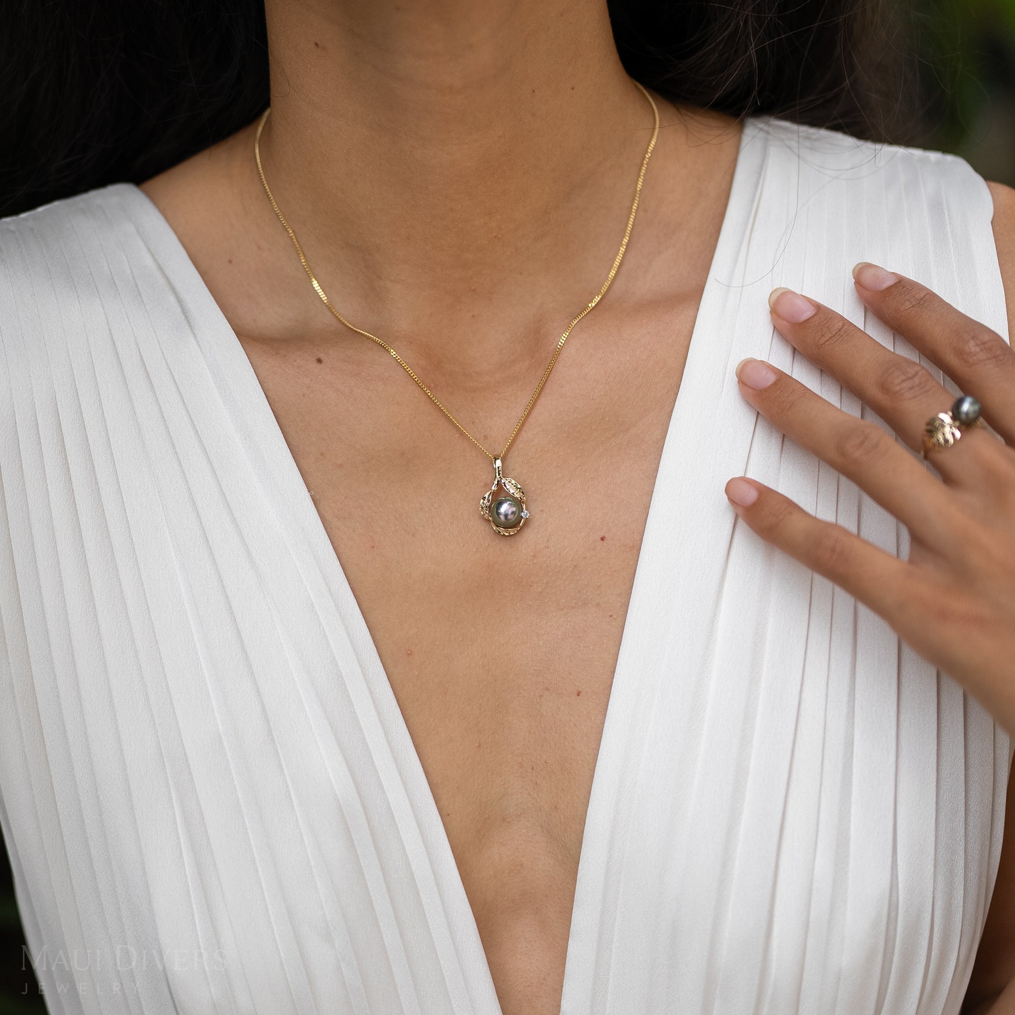 Close up of Model Wearing Maile Tahitian Black Pearl Pendant in Gold with Diamonds in white dress