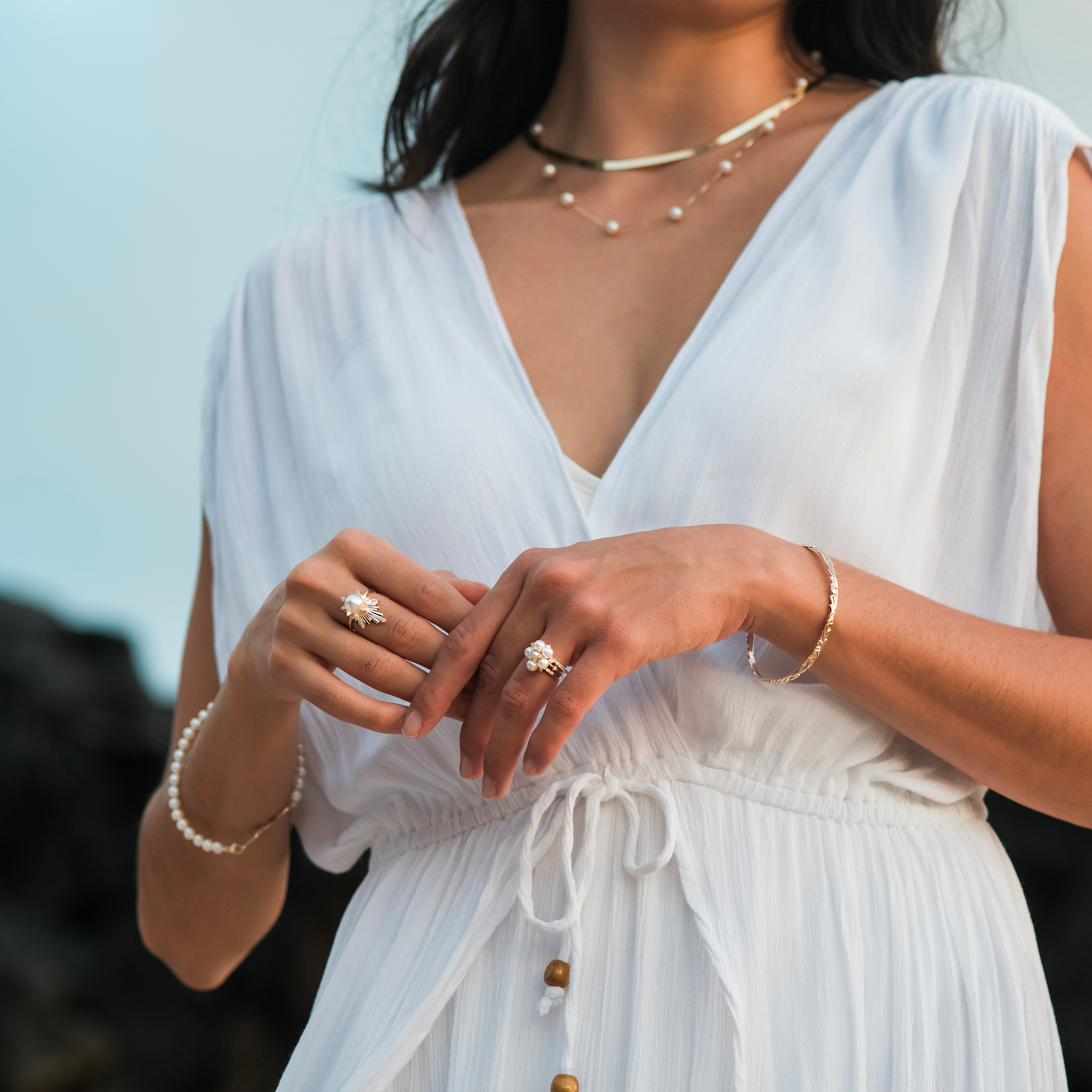 Woman wearing a white dress and Hawaiian Heirloom Old English Scroll Bracelet in Gold outdoors