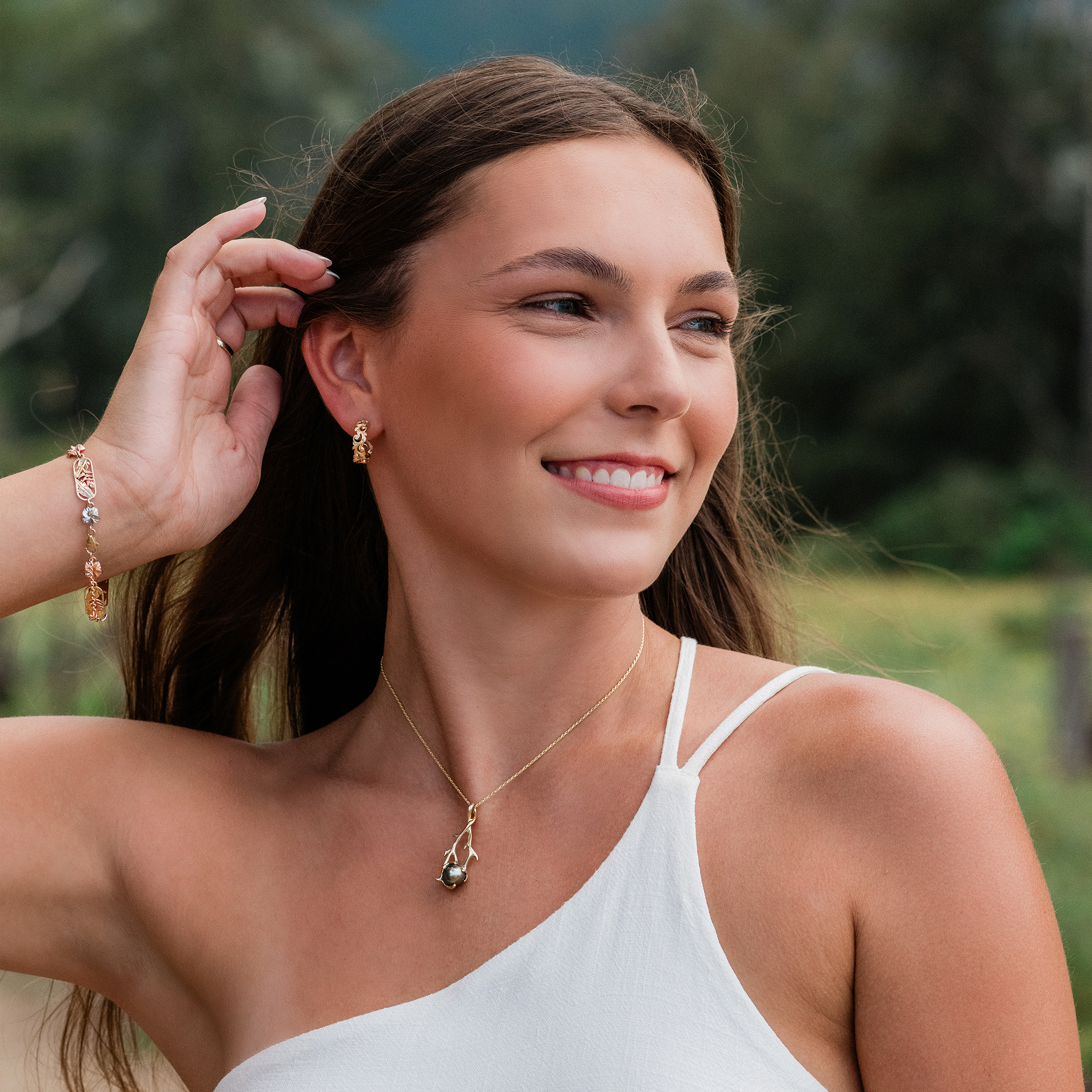 Woman wearing Living Heirloom Hoop Earrings in 14k Yellow Gold with Diamonds and a pearl pendant outdoors