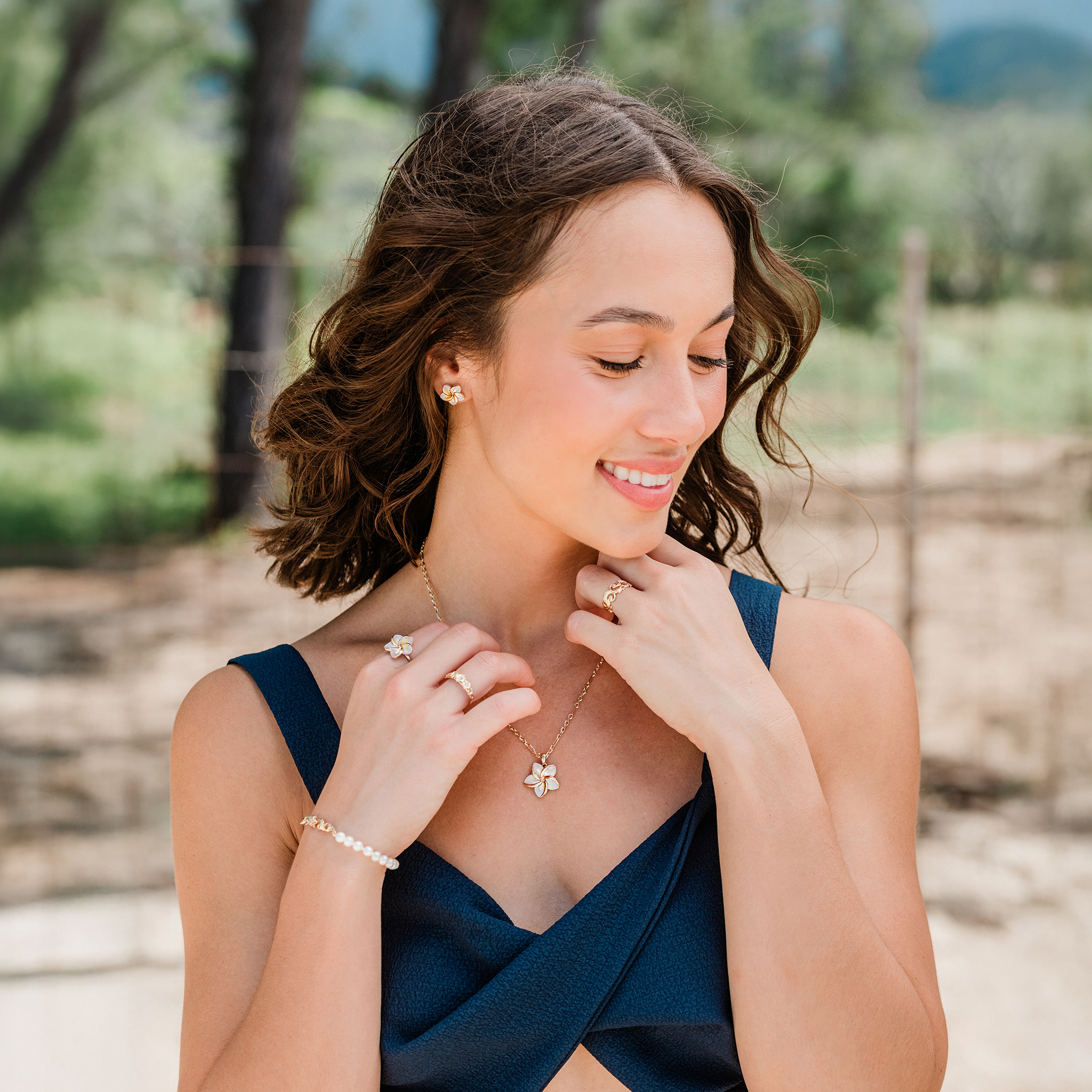Woman on beach wearing Plumeria Mother of Pearl Ring, pendant and earrings in 14k Yellow Gold