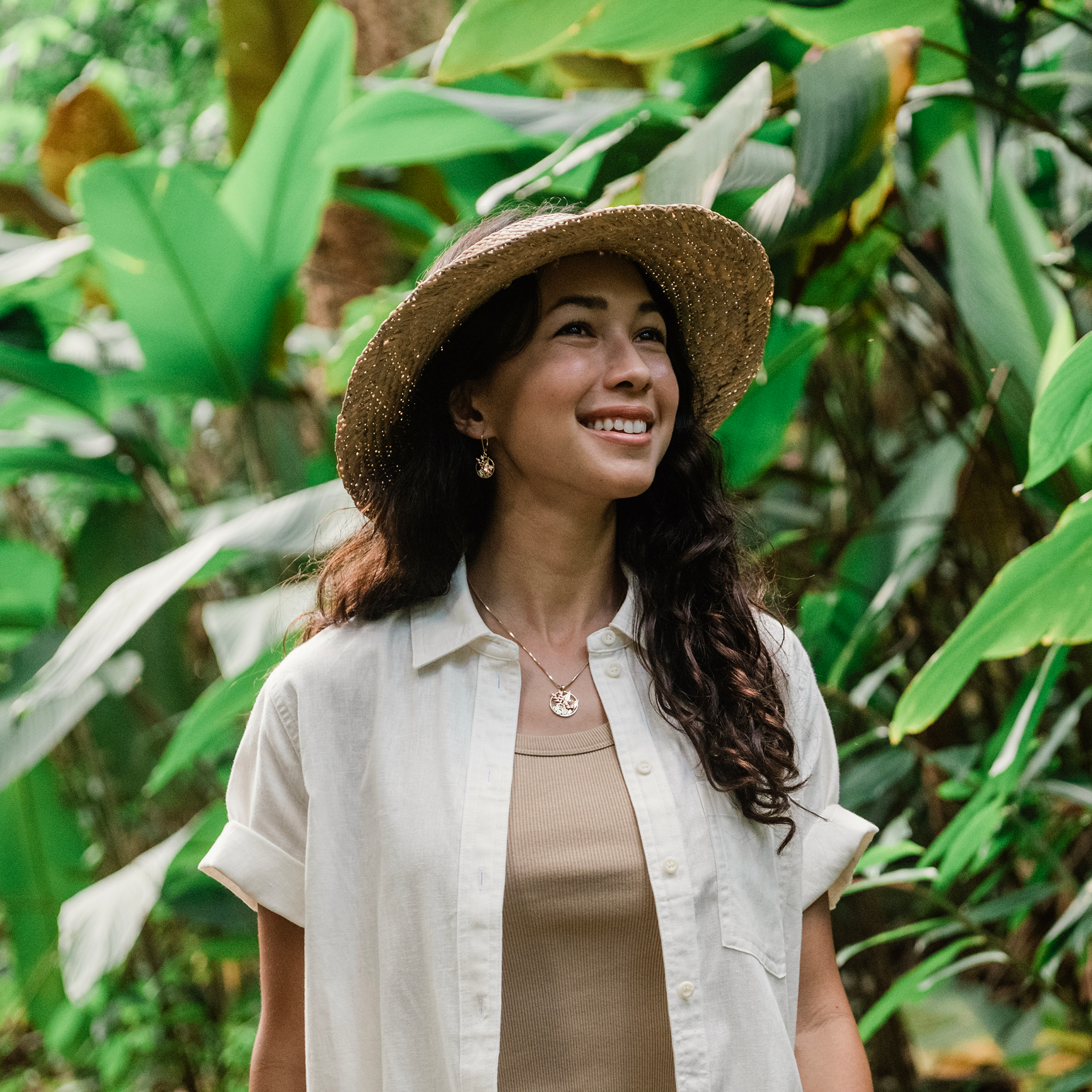 Woman in a tropical garden wearing a Hawaiian Gardens Hibiscus Pendant with matching earrings