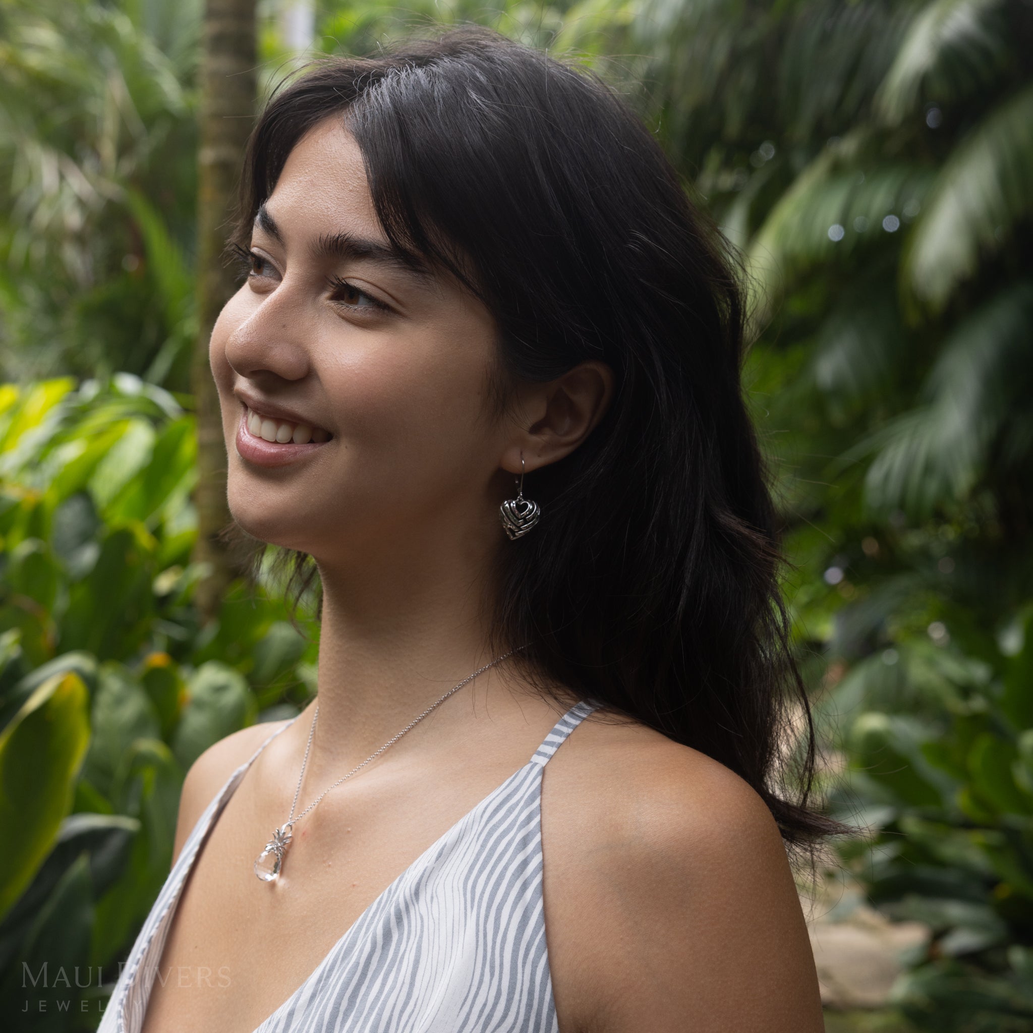 Woman in a garden wearing Aloha Heart Earrings in Sterling Silver