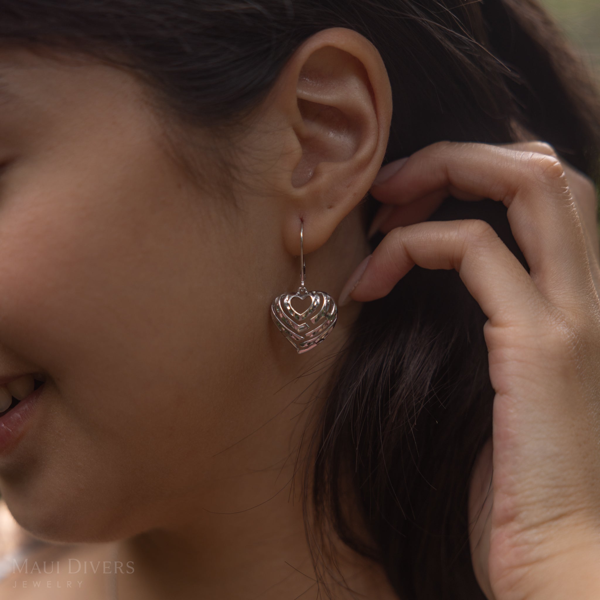 Close up of womanʻs ear with the Aloha Heart Earrings in Sterling Silver