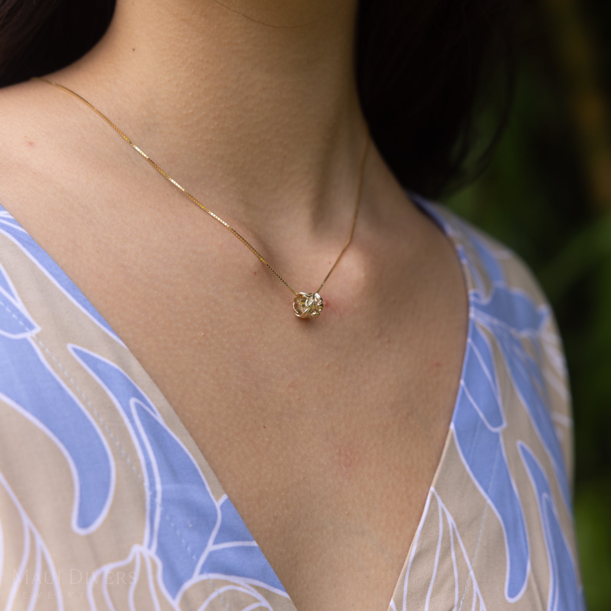 Close up of Hawaiian Heirloom Maile Scroll Barrel Pendant in Gold on a woman's chest