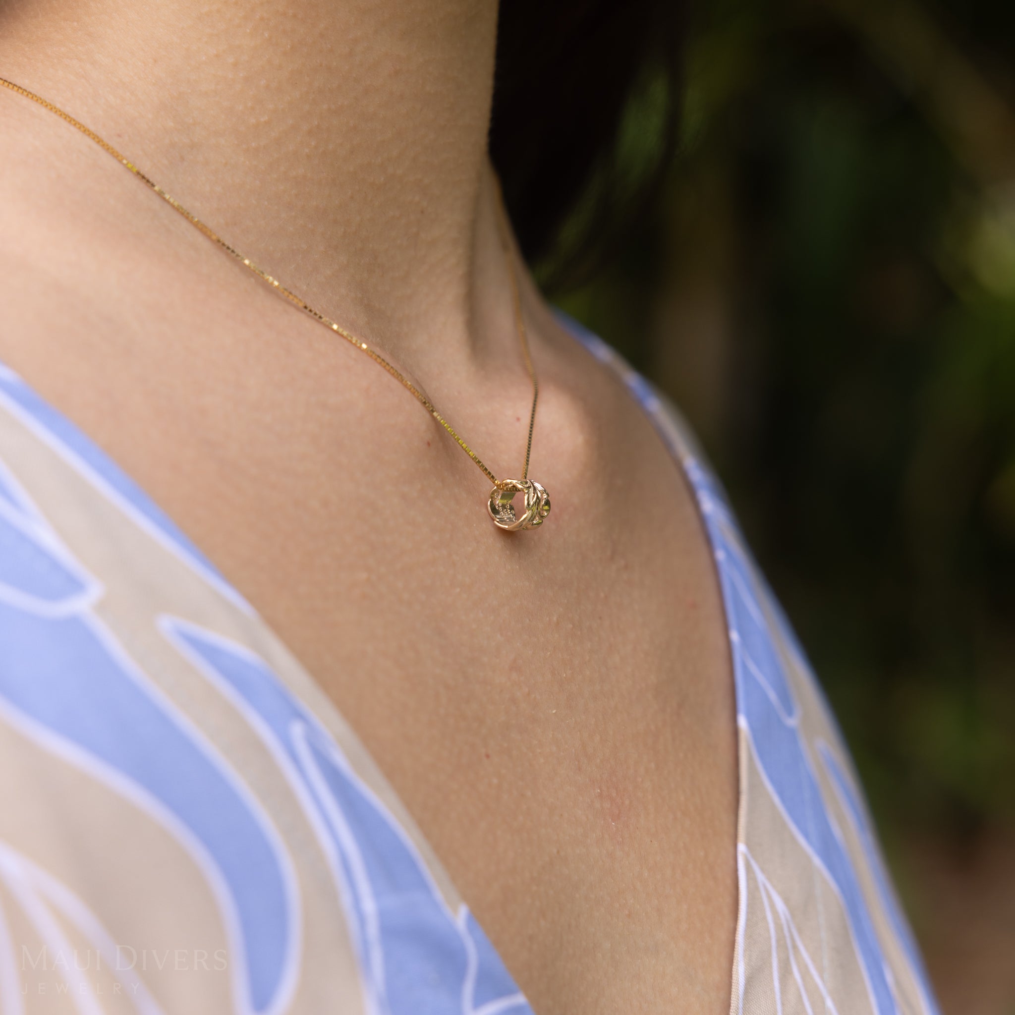 Side view of Hawaiian Heirloom Maile Scroll Barrel Pendant in Gold on a woman's chest