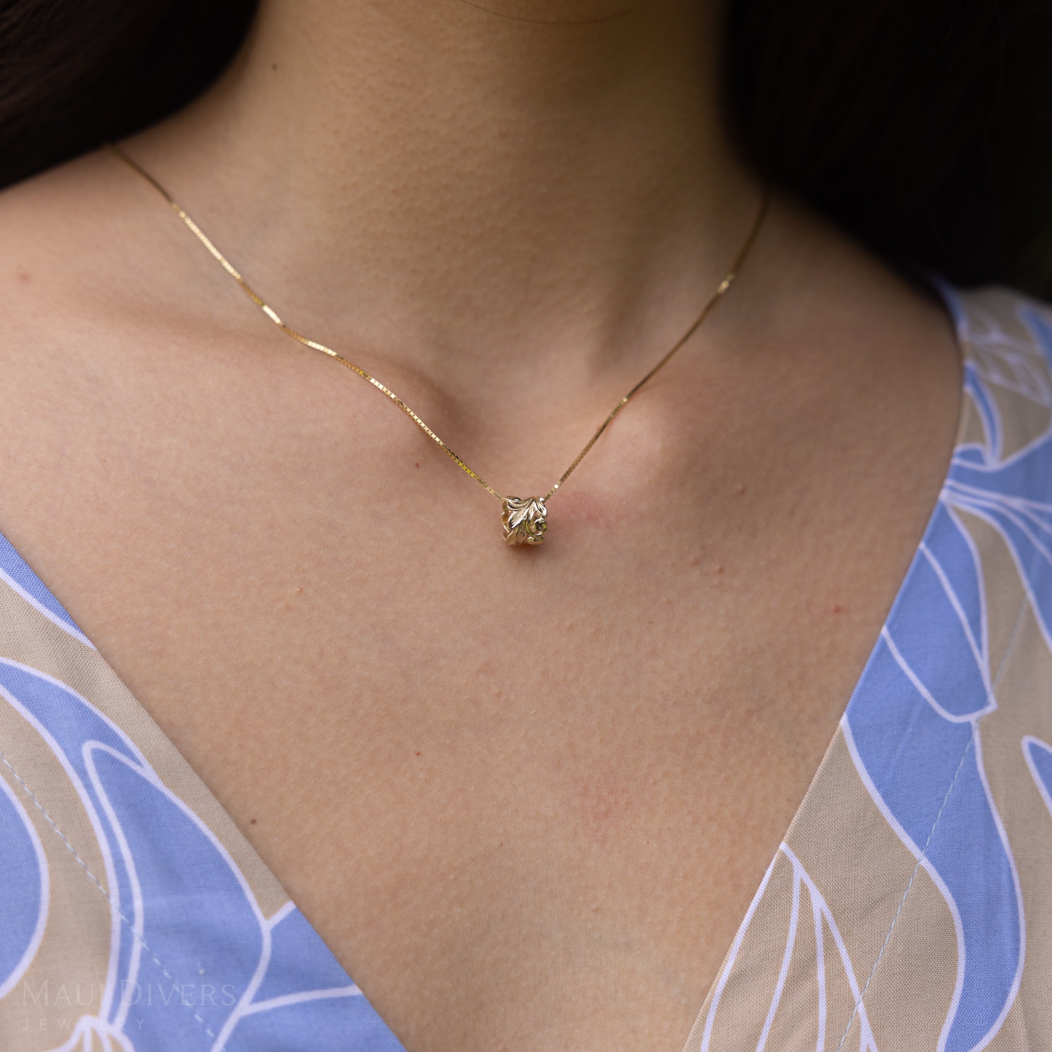 Close up of Hawaiian Heirloom Maile Scroll Barrel Pendant in Gold on a woman's chest