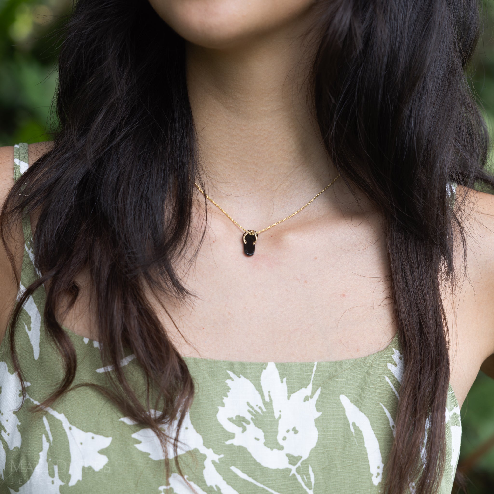 Woman wearing a Hawaiian Black Coral Slipper Pendant with 14k Yellow Gold Straps
