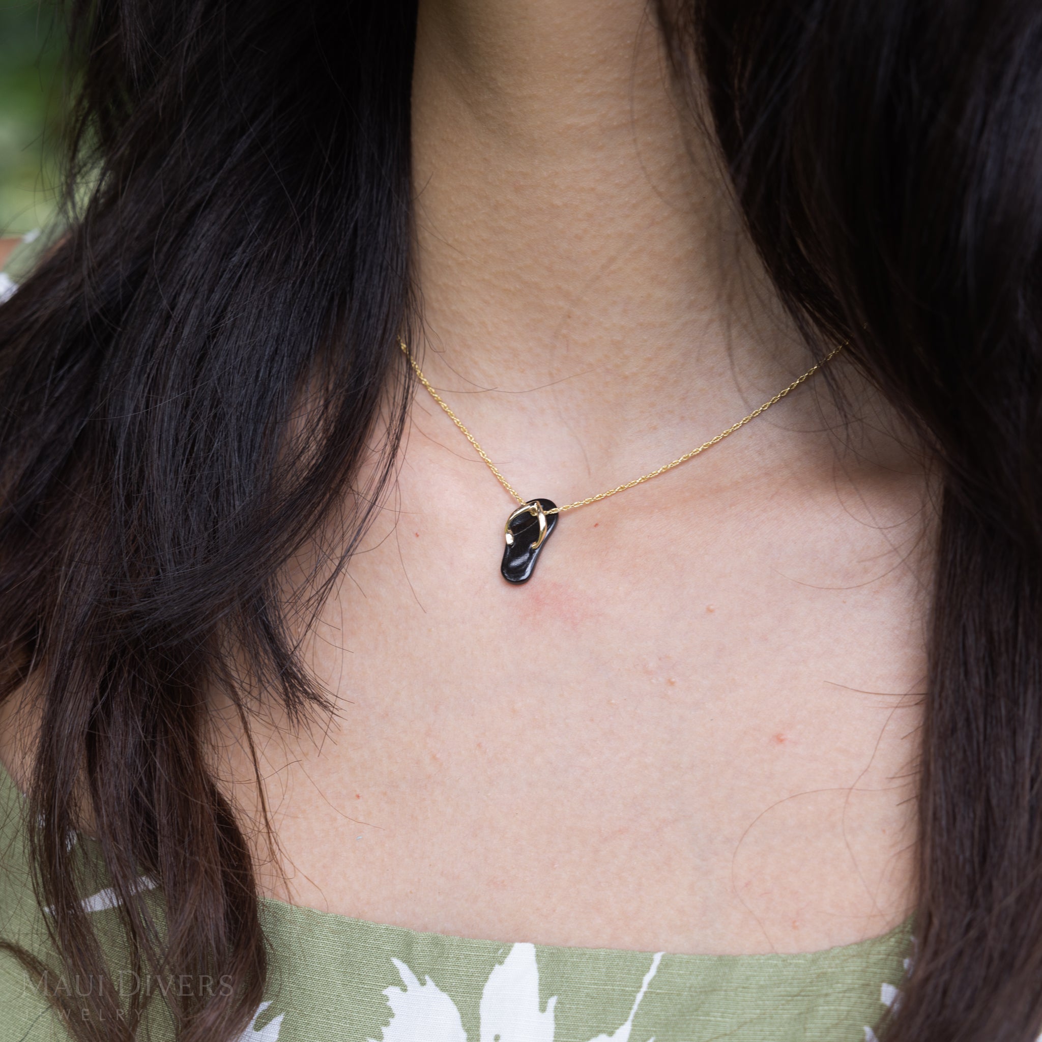 Woman wearing a Hawaiian Black Coral Slipper Pendant with 14k Yellow Gold Straps