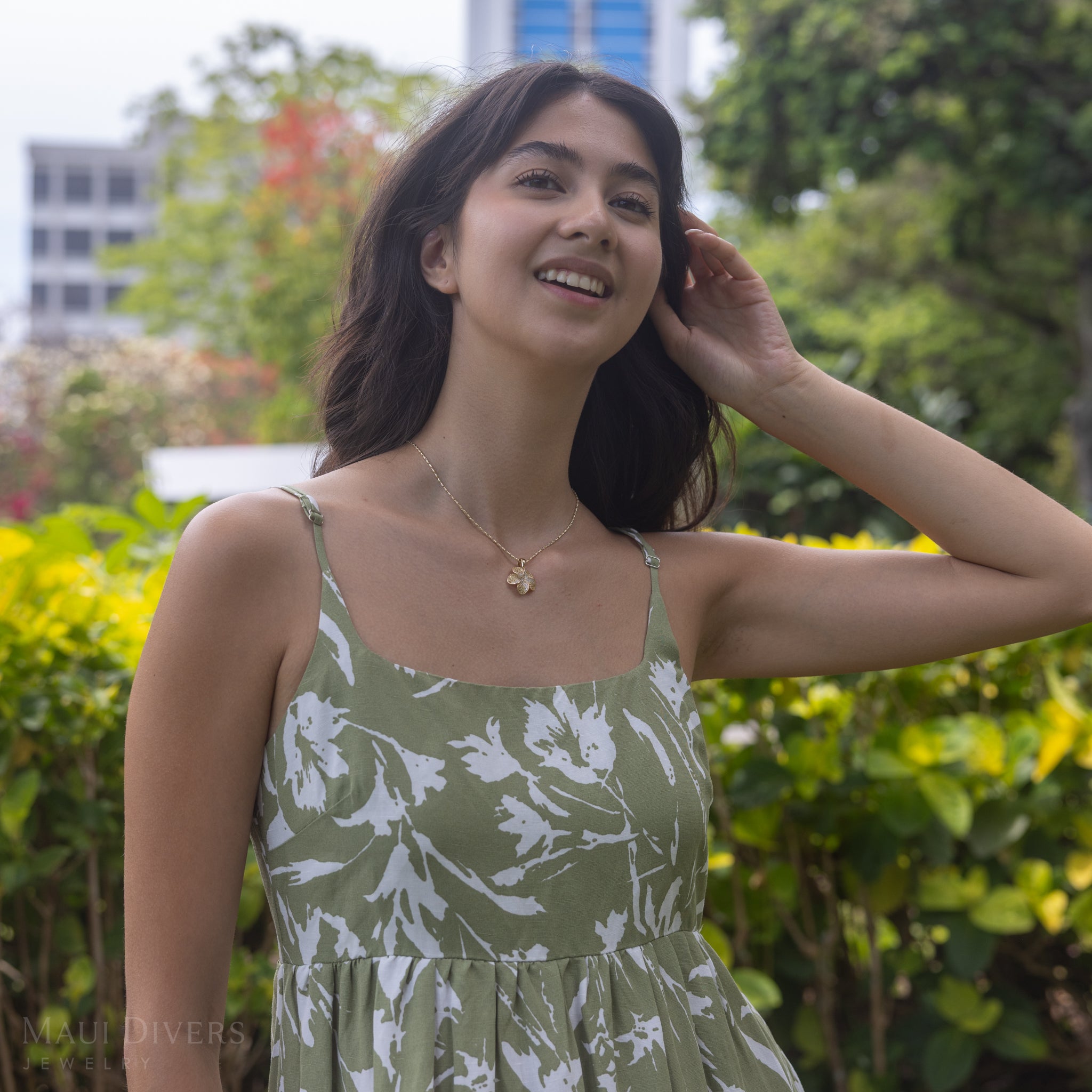 Woman in an urban garden wearing a Plumeria Yellow Sapphire Pendant in Gold with Diamonds