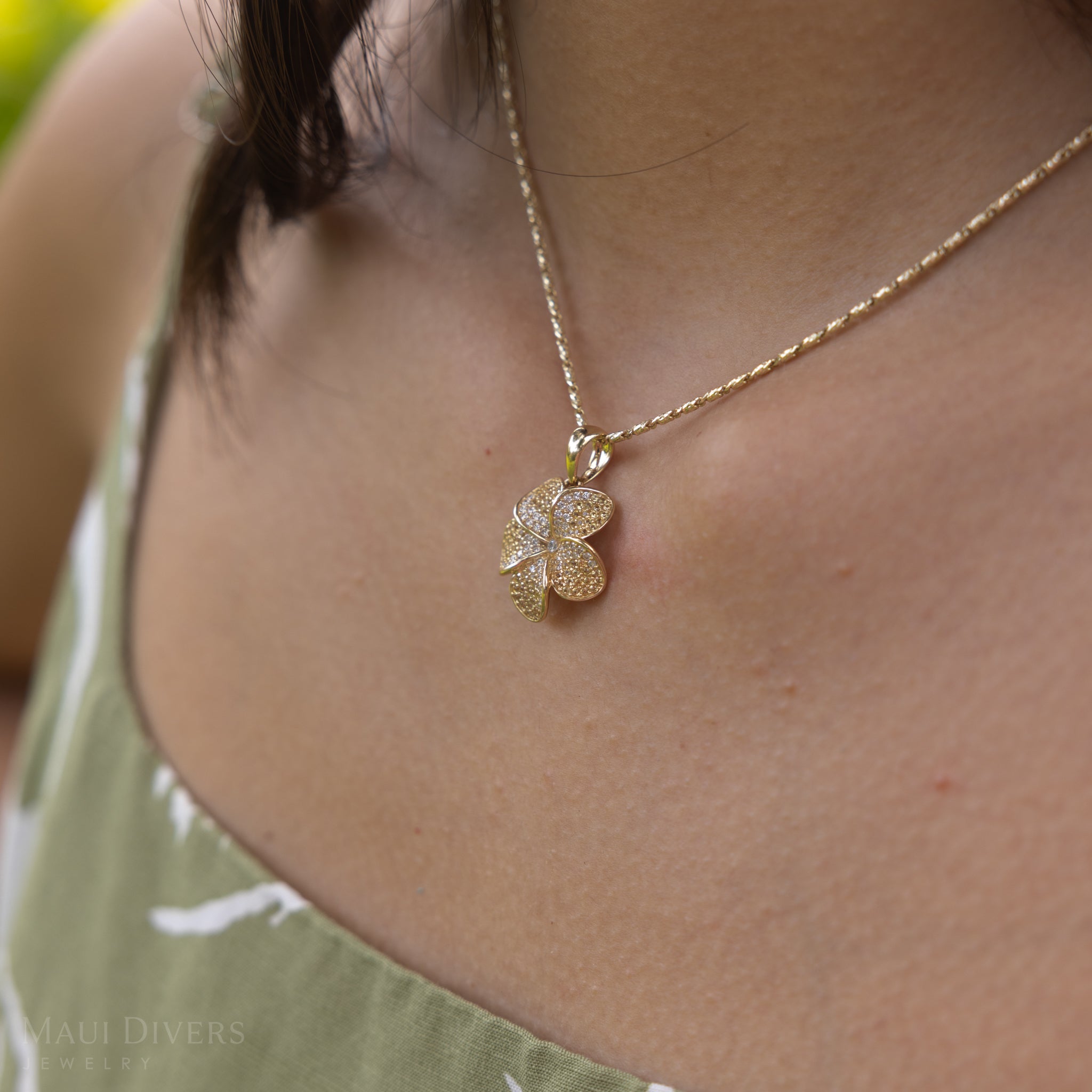 Close up of a Plumeria Yellow Sapphire Pendant in Gold with Diamonds on a woman's chest