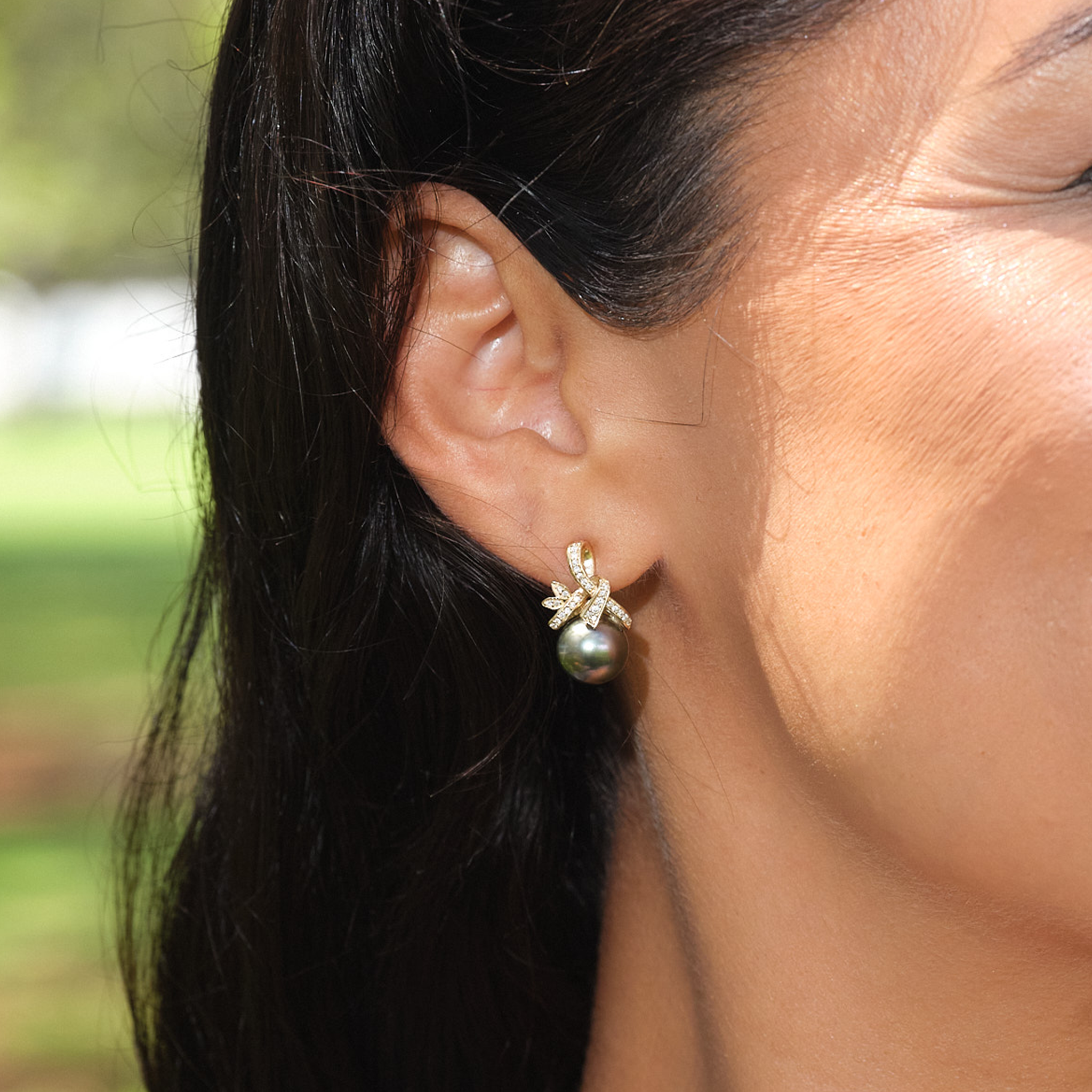 A woman's ear with Tahitian Black Pearl Earrings in Gold with Diamonds - 9-10mm - Maui Divers Jewelry