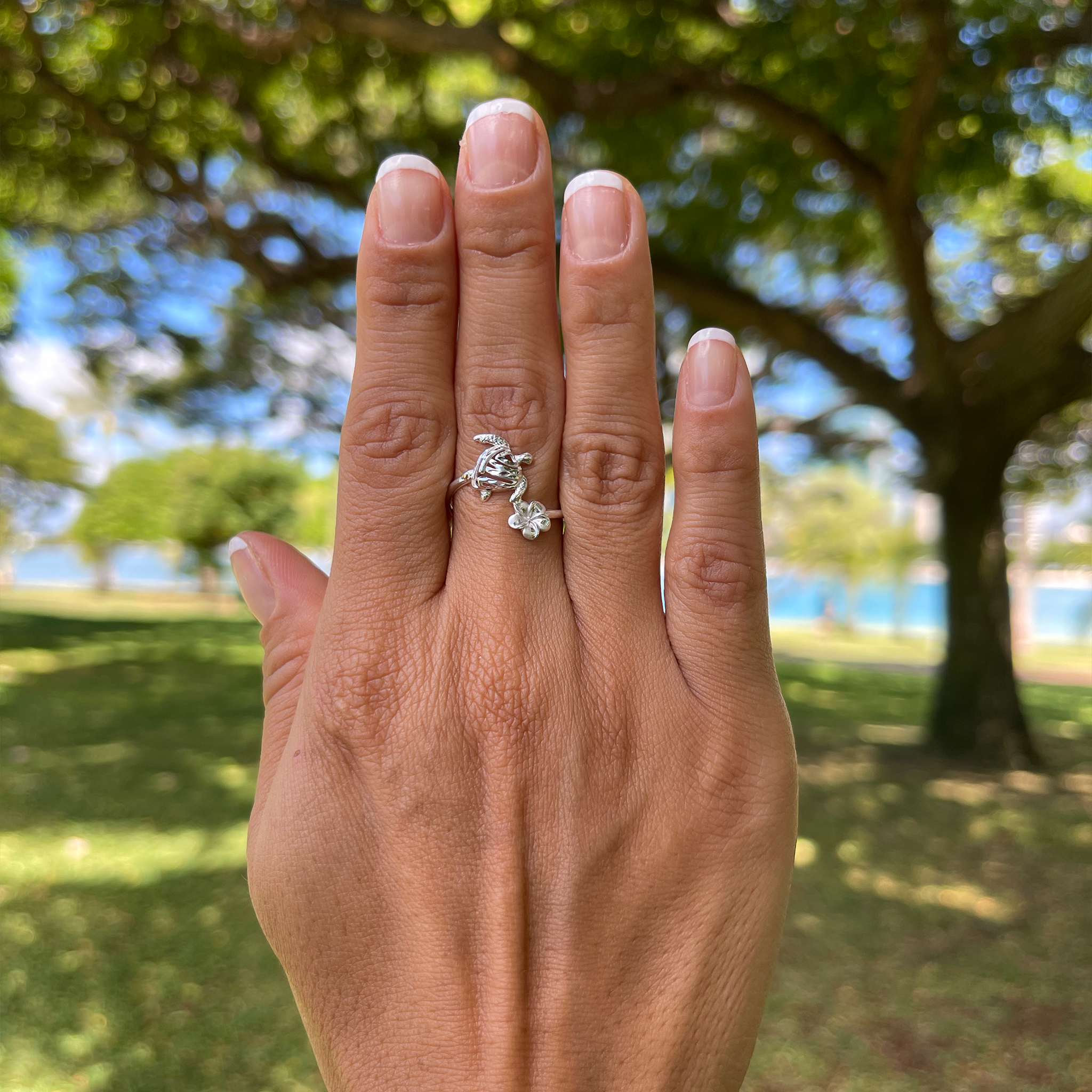 a woman's hand with a Honu and Plumeria Ring in Sterling Silver from Maui Divers Jewelry on it.