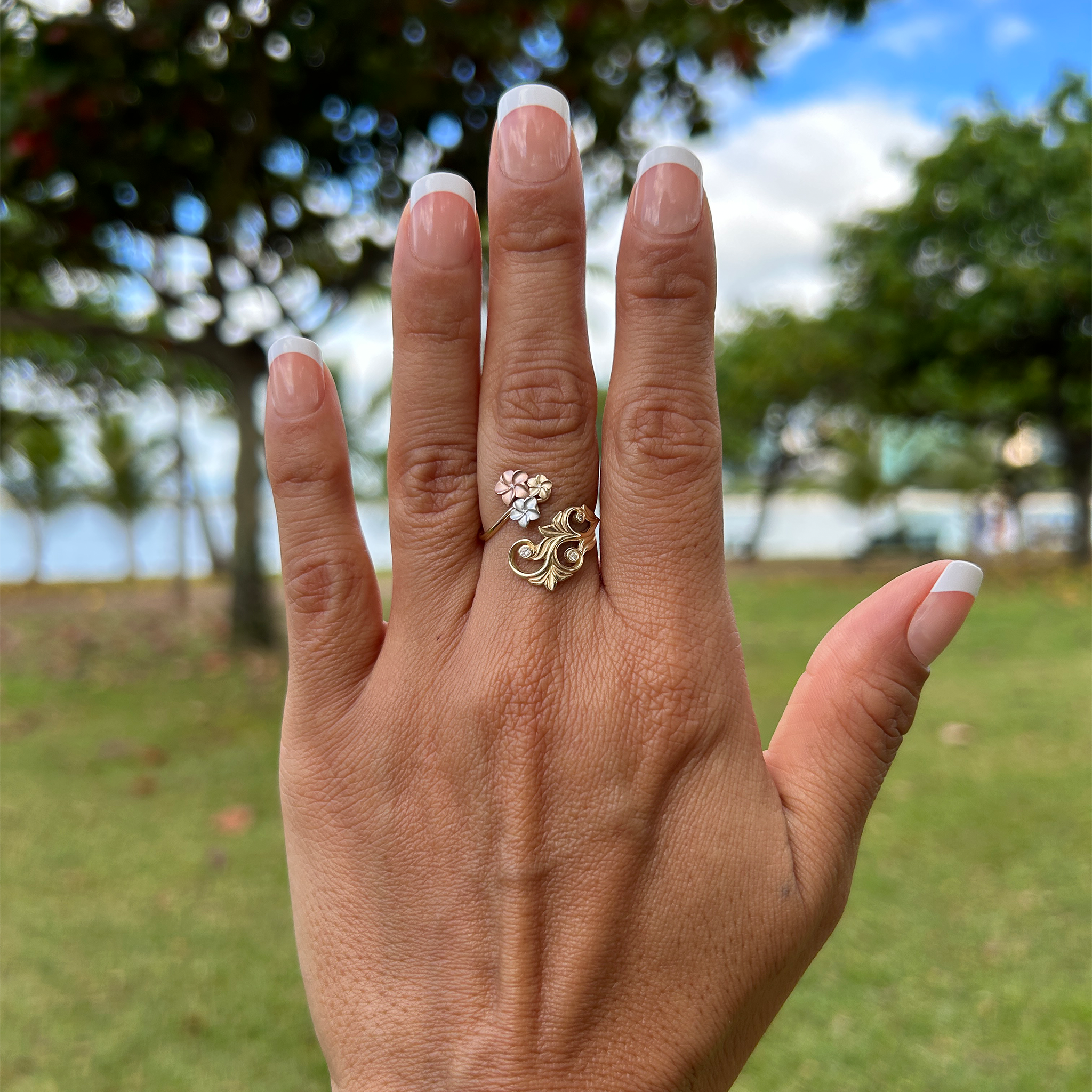 A woman's hand wearing a Living Heirloom Plumeria Ring in Tri Color Gold with Diamonds - Maui Divers Jewelry