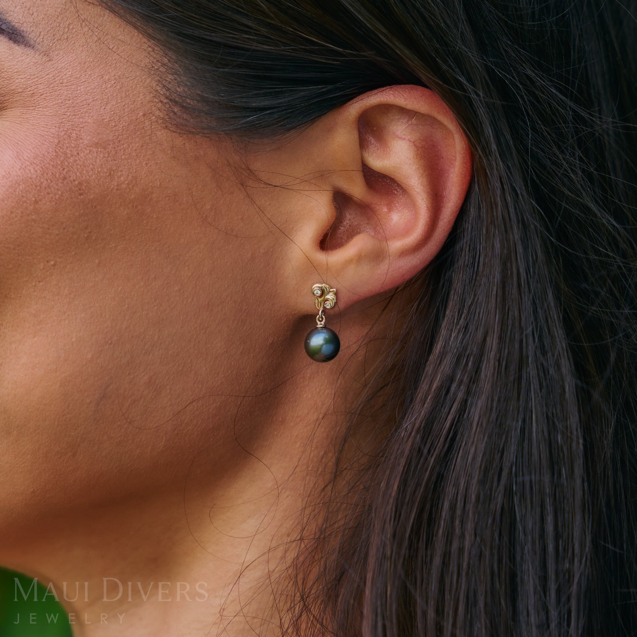 Close-up of an ear wearing a black pearl earring with a gold Living Heirloom setting.