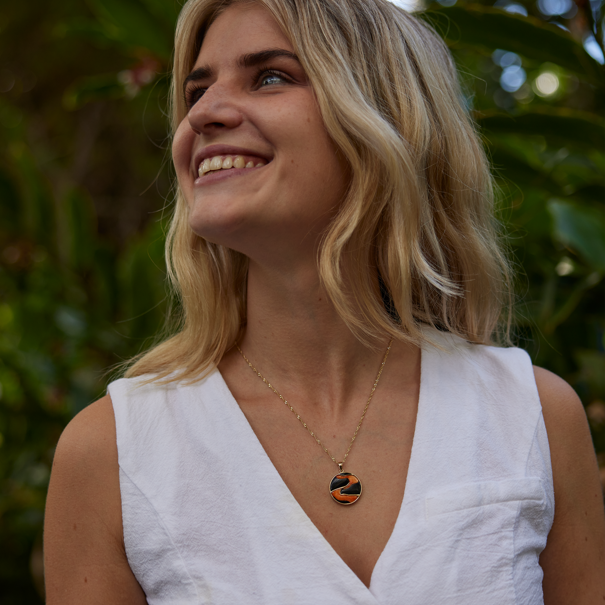 溶岩流ブラックコーラルとスパイニーオイスターのペンダント(ゴールド)を身につけた庭の女性 - 22mm