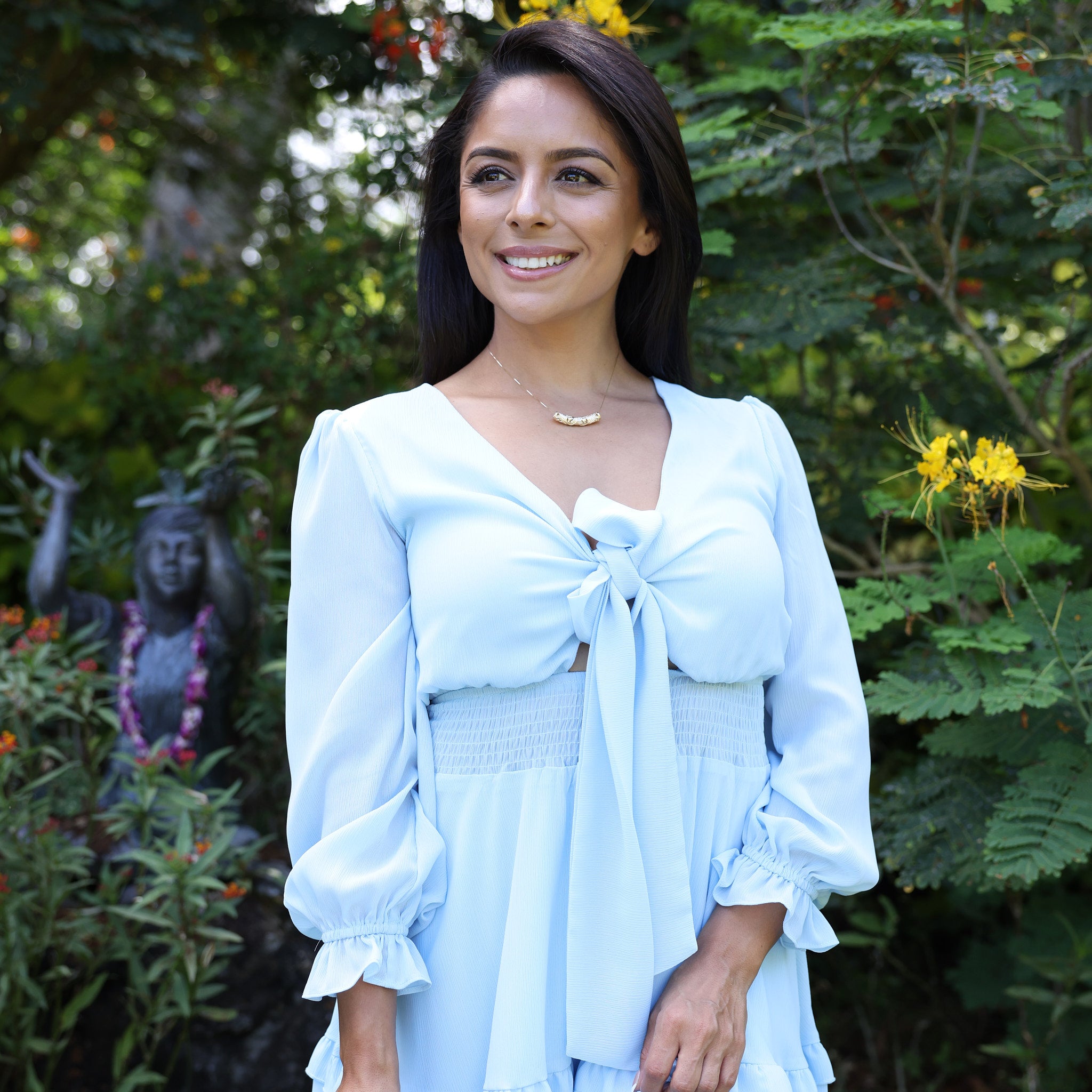 プルメリア ゴールド 37mm を身に着けた青いドレスの女性(熱帯植物園にて