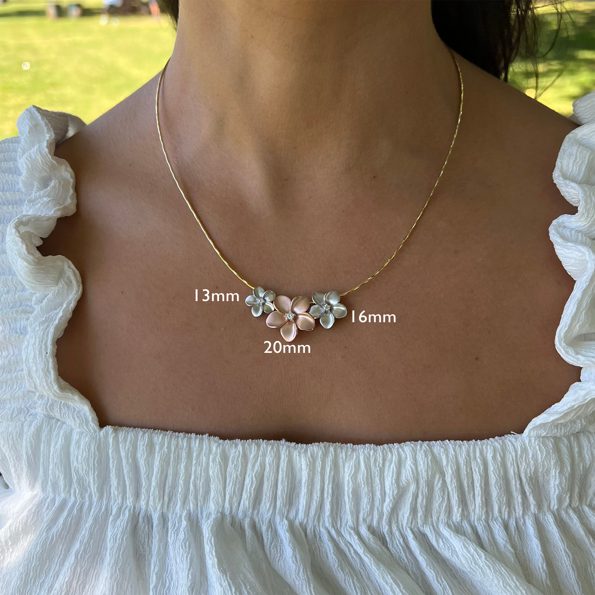 ホワイトゴールドのプルメリア ローズゴールドのプルメリア (モデル、背景は草地、目盛付き