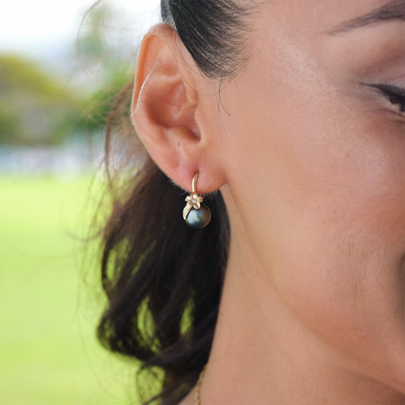 A woman's ear with Plumeria Tahitian Black Pearl Earrings in Gold with Diamonds - 8-9mm - Maui Divers Jewelry