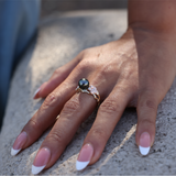 Maui Divers Jewelry Pearls in Bloom Plumeria Tahitian Black Pearl Ring in Tri Color Gold with Diamonds on Hand touching cement wall