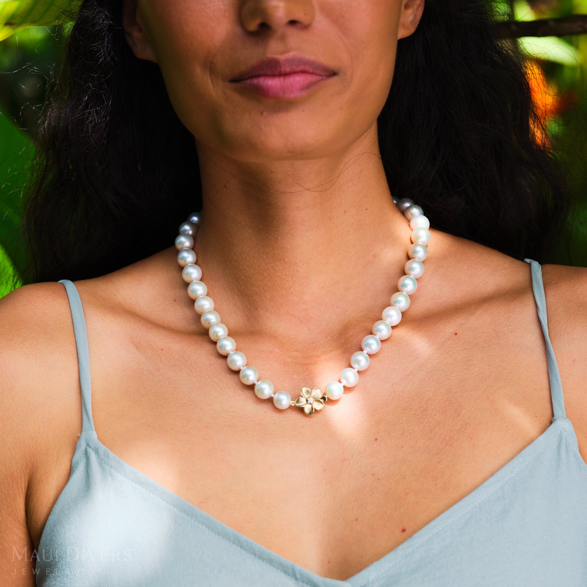 Woman wearing a pearl necklace with a blurred natural background